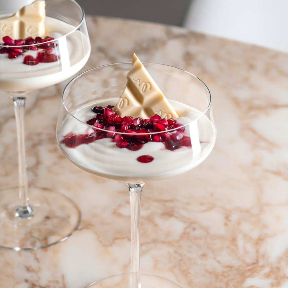 Cremiges Dessert mit Granatapfelkernen und weißer Schokolade in einem Glas.