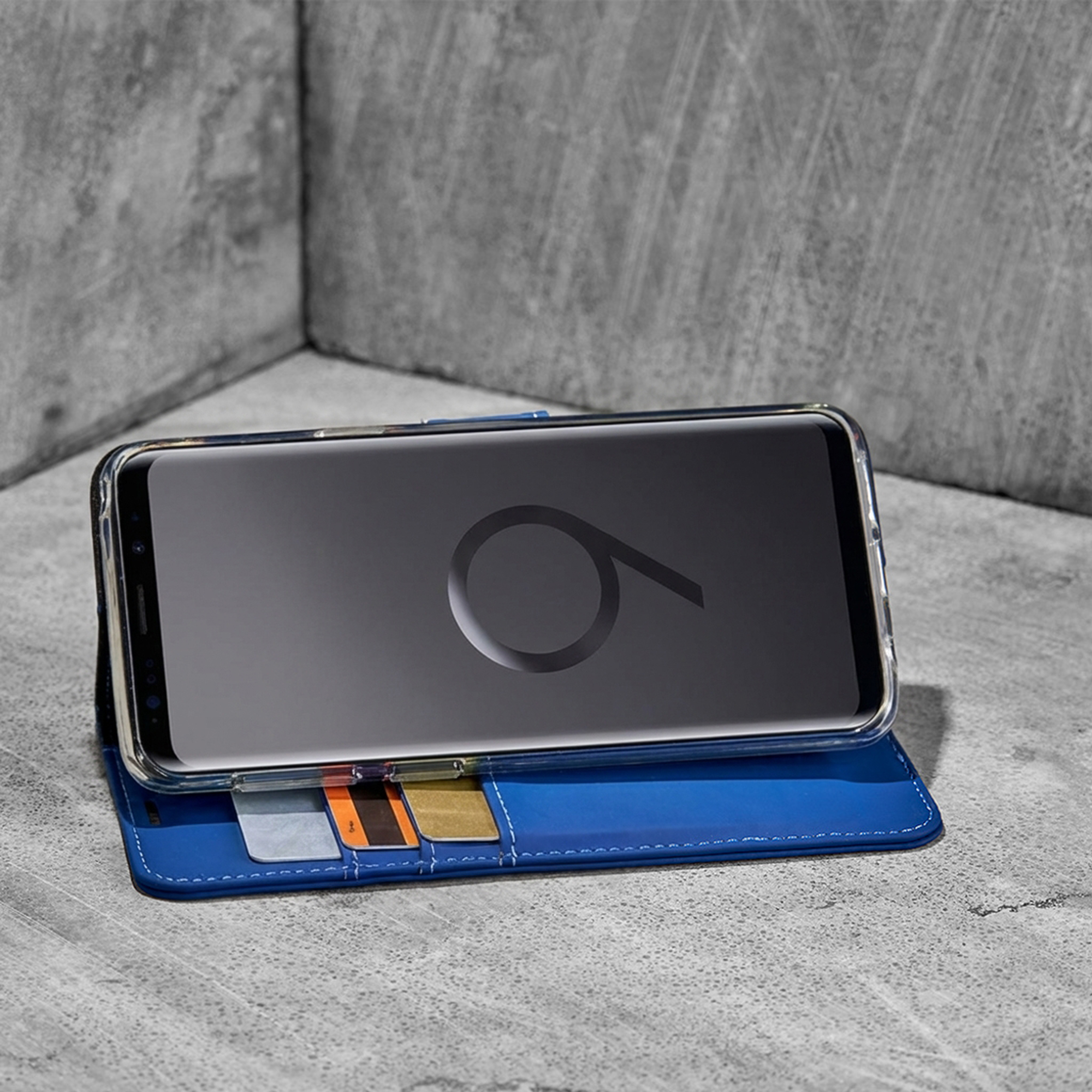 Una custodia blu per smartphone con fessure per carte su cemento.