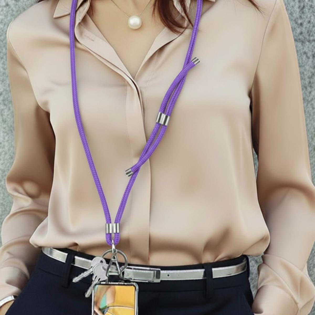 Frau in beige Seidenbluse mit lila Lanyard, Schlüsseln und Handyhülle.