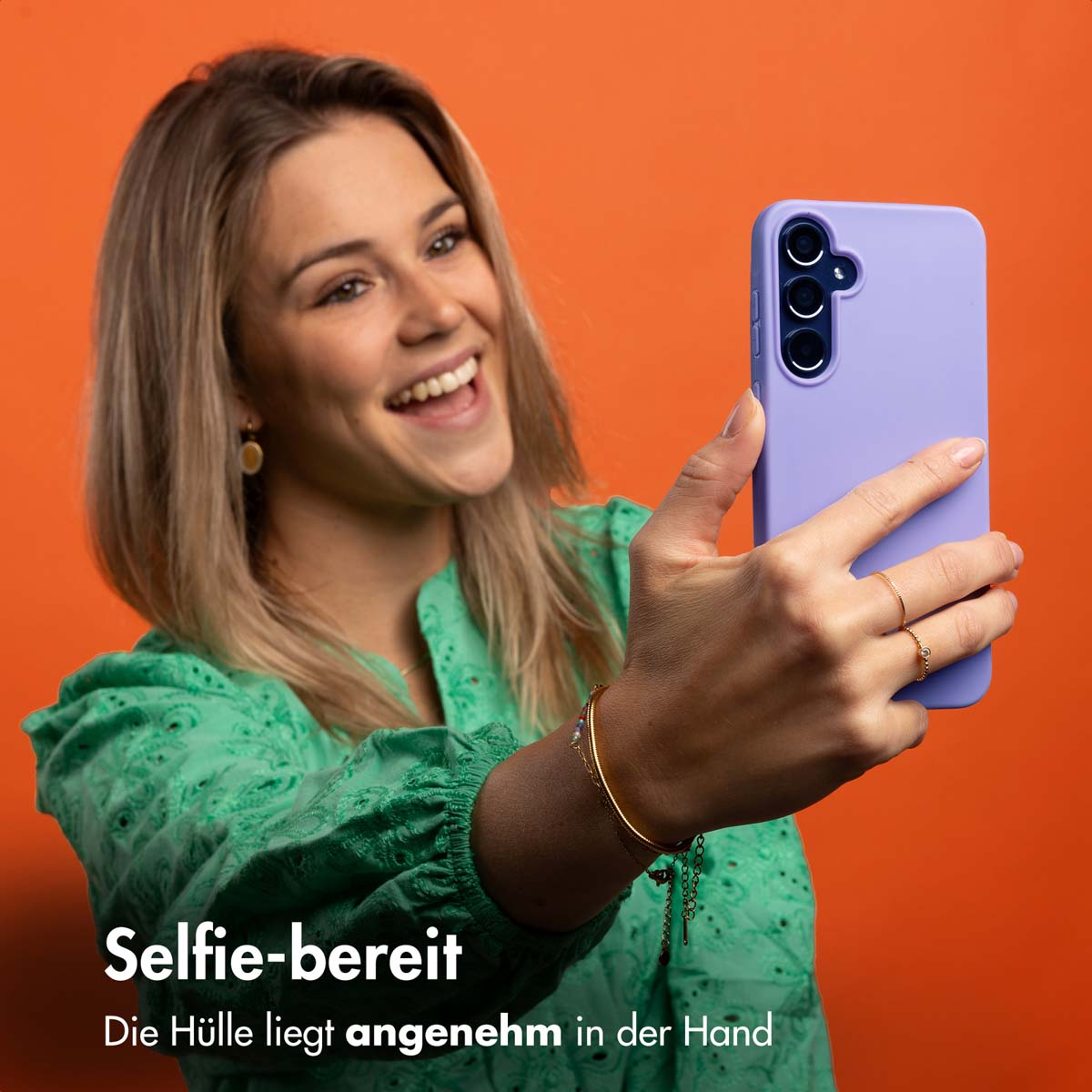 Vrouw in groen shirt glimlacht terwijl ze een selfie maakt met paarse telefoonhoes.