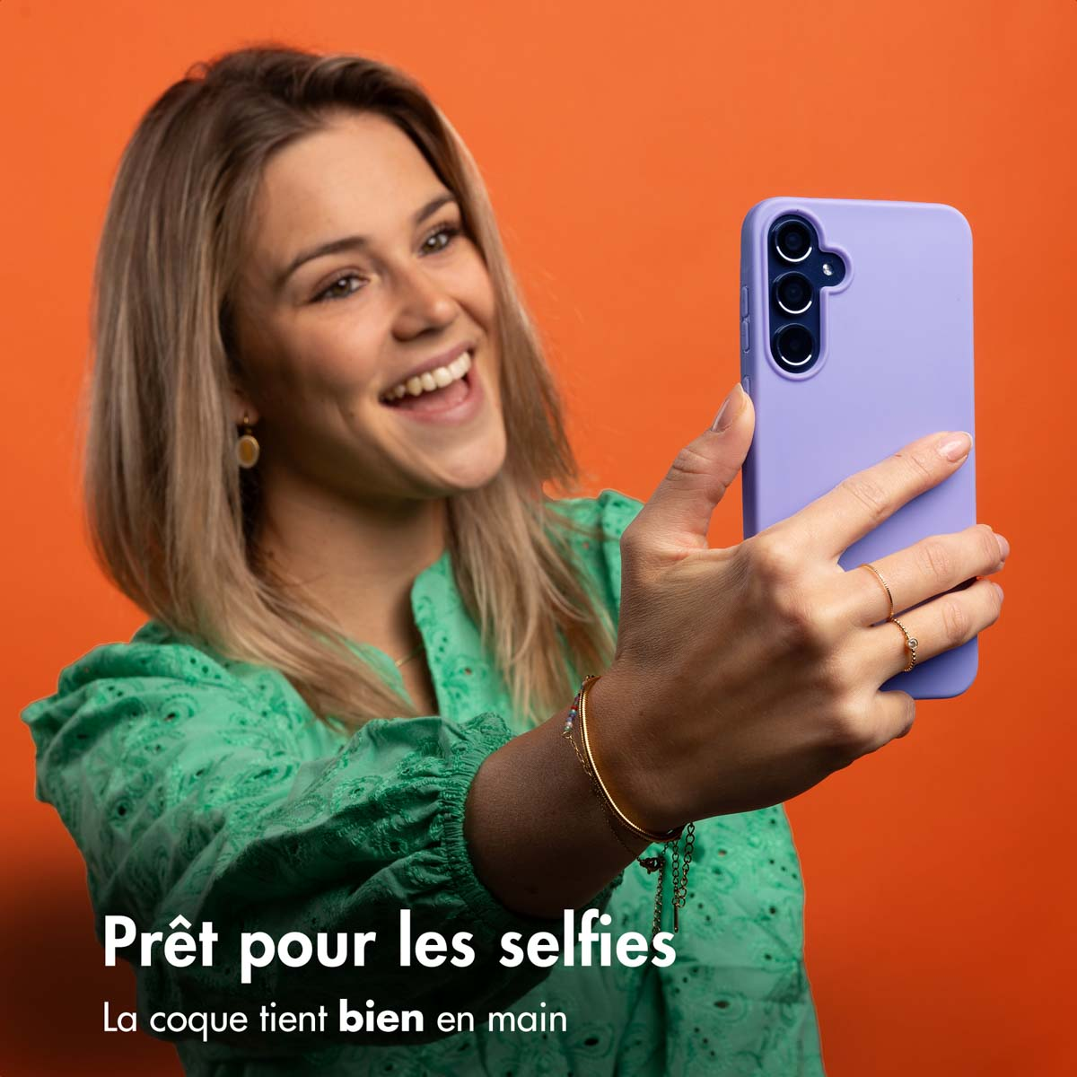 Een blonde vrouw maakt een selfie met een paarse telefoon.