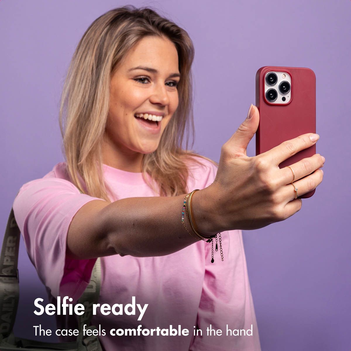 Donna si fa un selfie con cover rossa, sorridendo, sfondo viola.