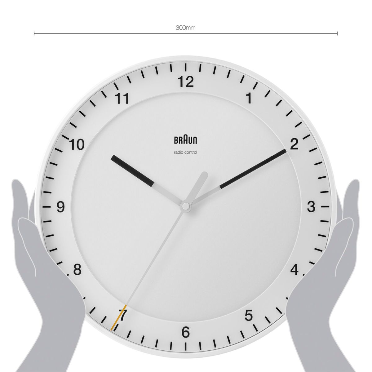 Reloj de pared blanco con manecillas y números negros, sostenido por manos.