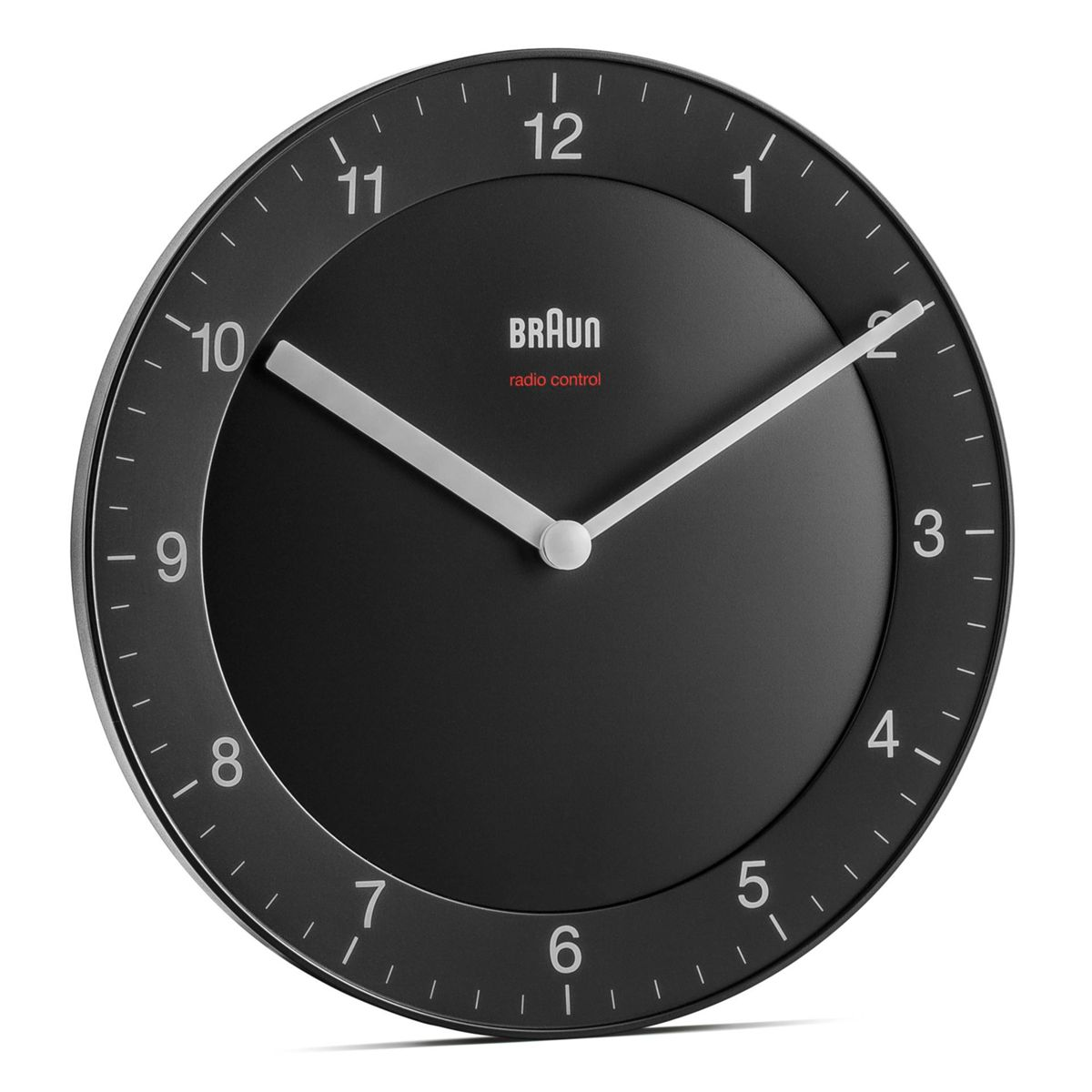 Un reloj de pared negro con números y manecillas blancas, la marca BRAUN es visible.