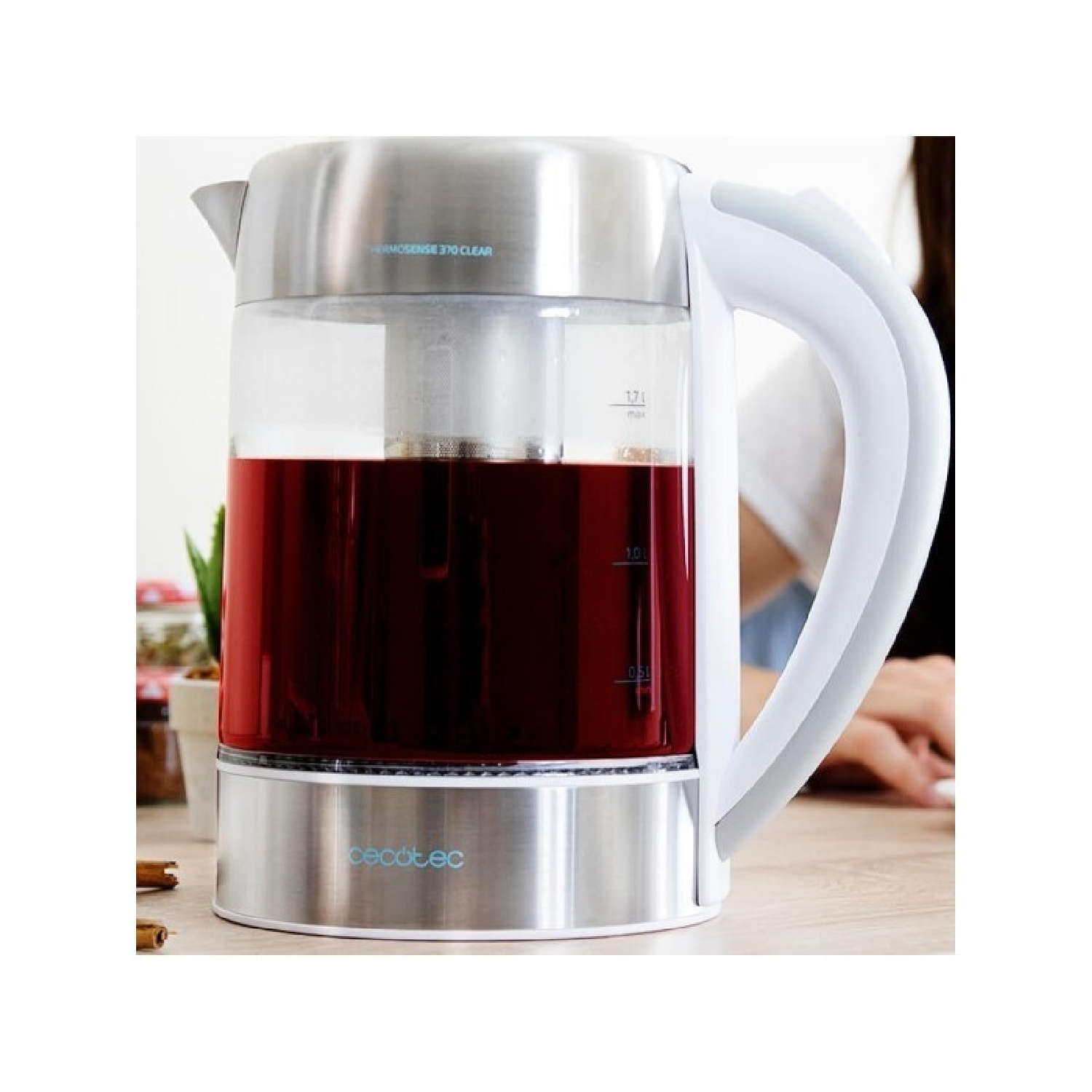 Ein Wasserkocher mit Glasbehälter, gefüllt mit rotem Tee, auf einem Holztisch.