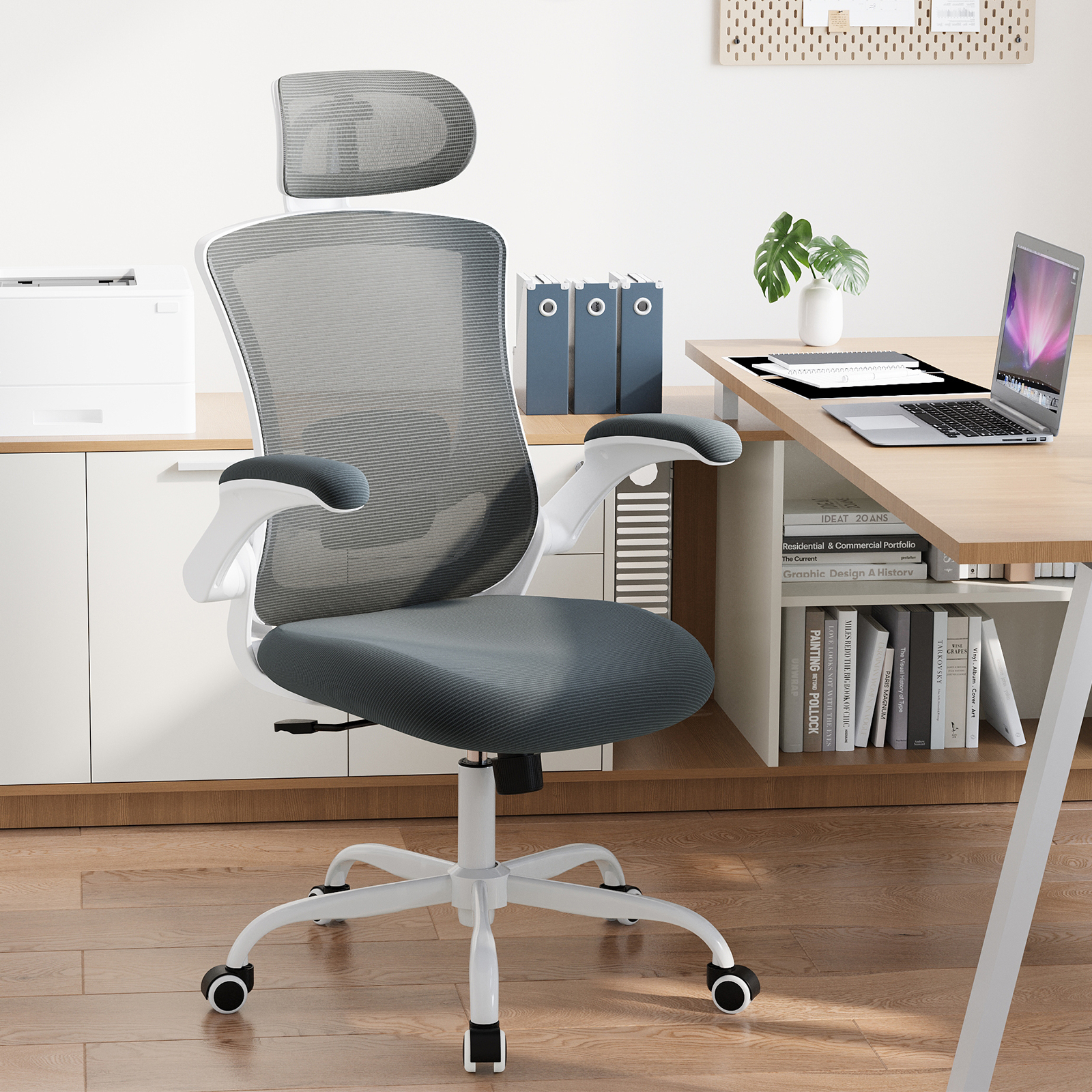 Una silla de oficina gris con reposacabezas y marco blanco sobre suelo de madera.