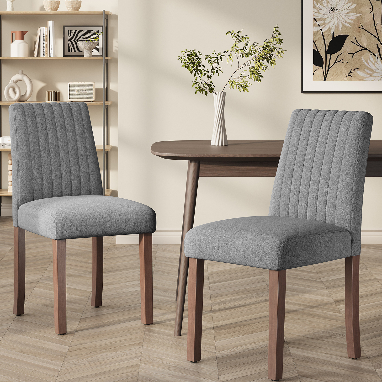 Due sedie da pranzo grigie imbottite con gambe in legno in una stanza con tavolo.