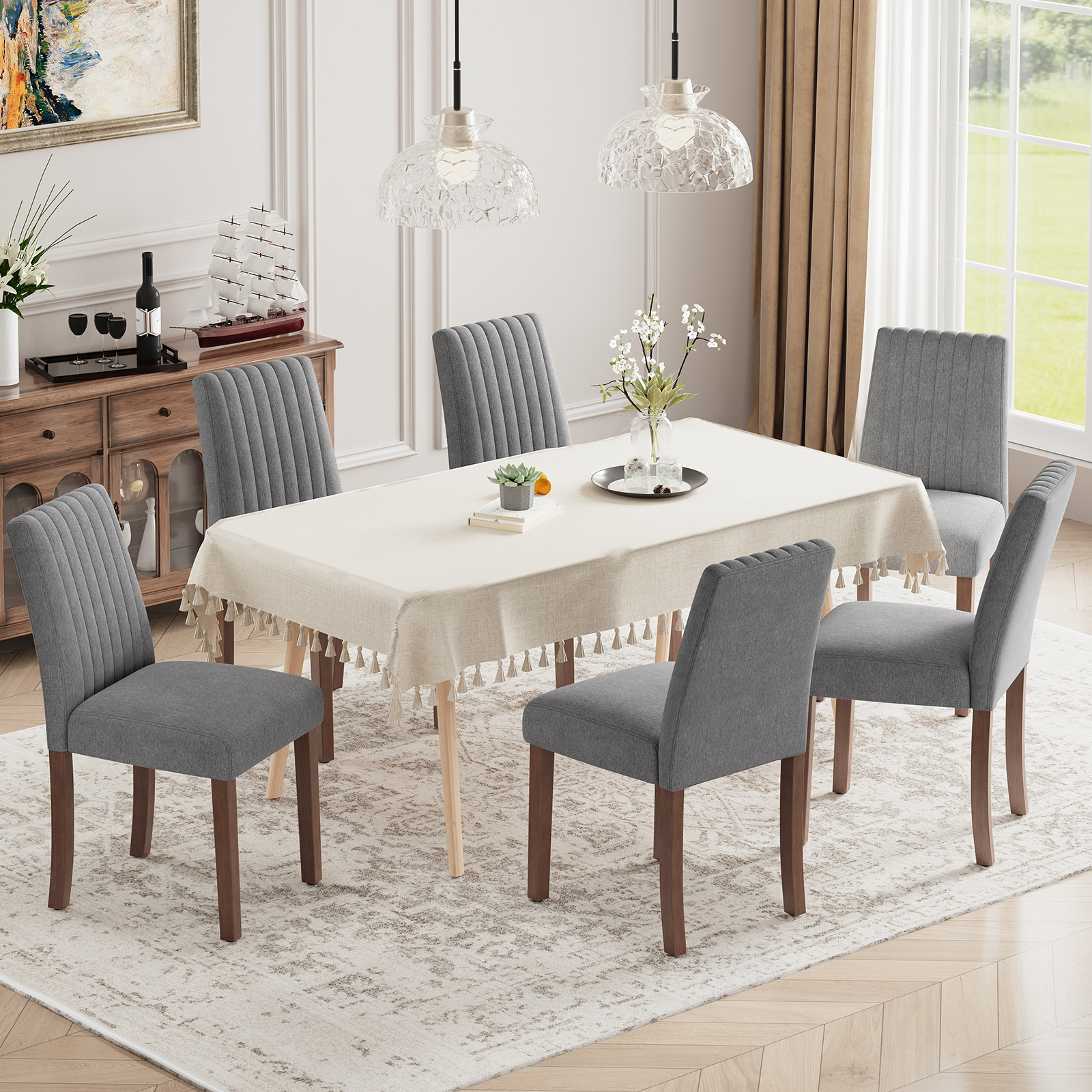 Una sala da pranzo con un tavolo, sei sedie grigie, un tappeto e una credenza.