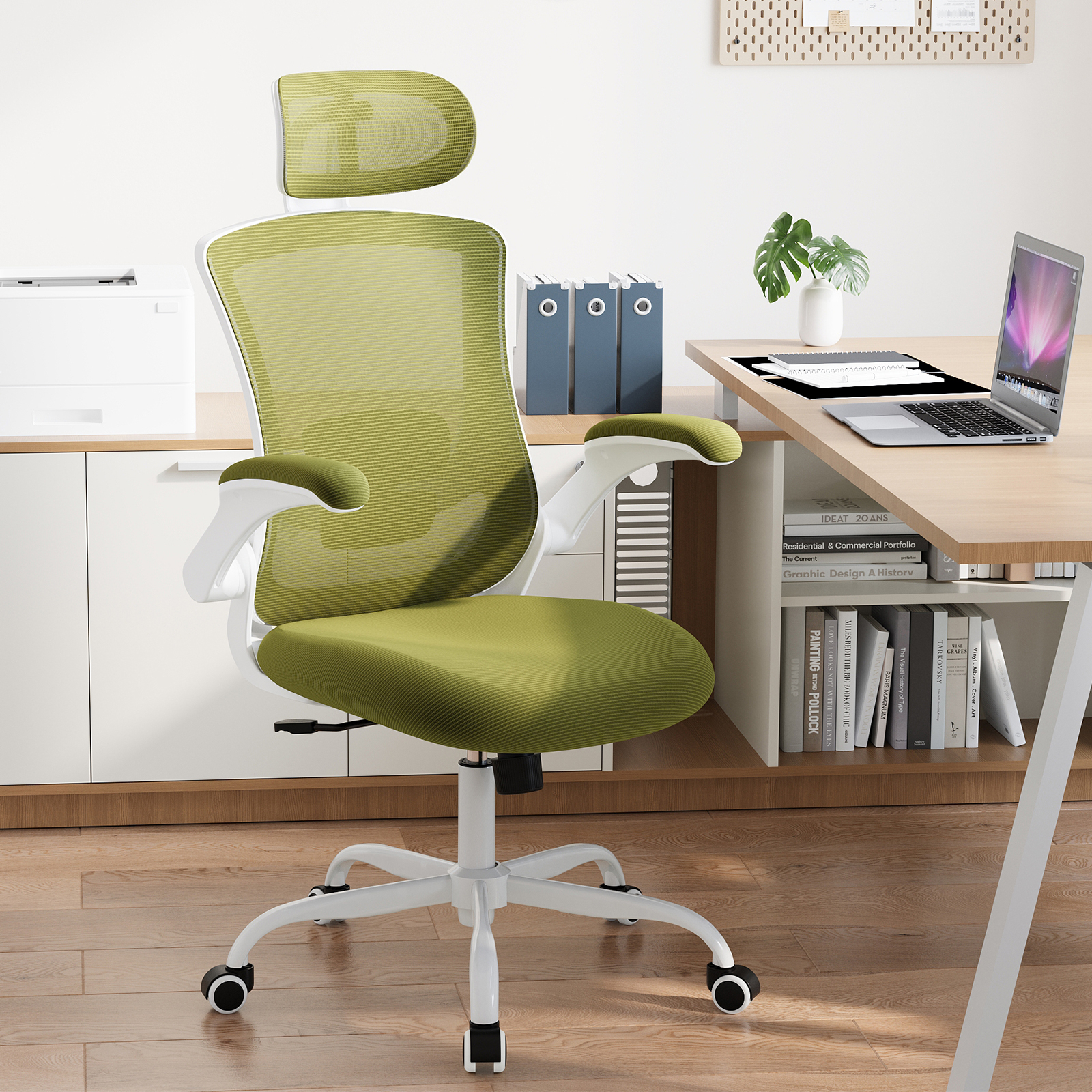 Silla de oficina verde con marco blanco, frente a un escritorio con portátil.