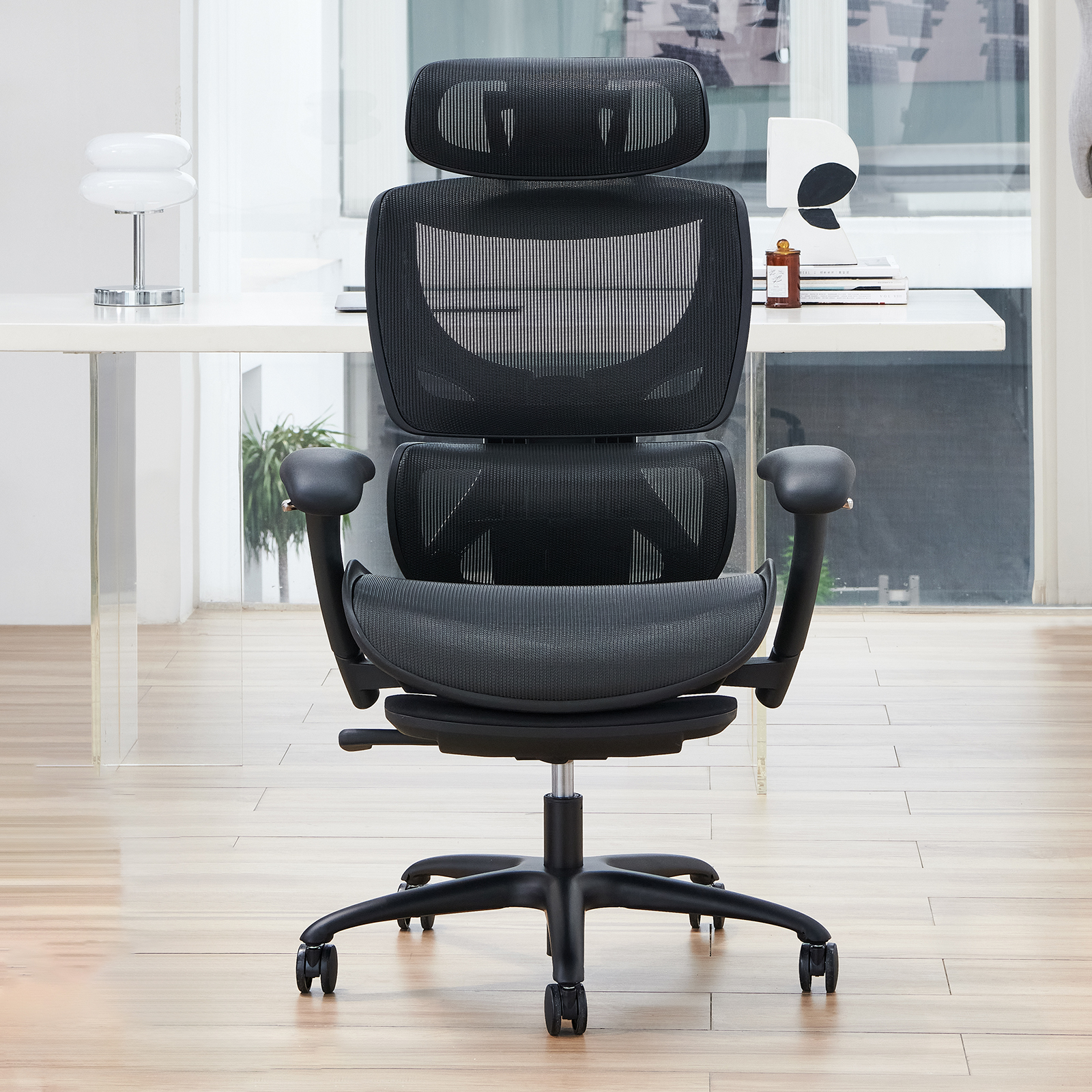 Una silla de oficina negra de malla con reposacabezas ajustable sobre suelo de madera.