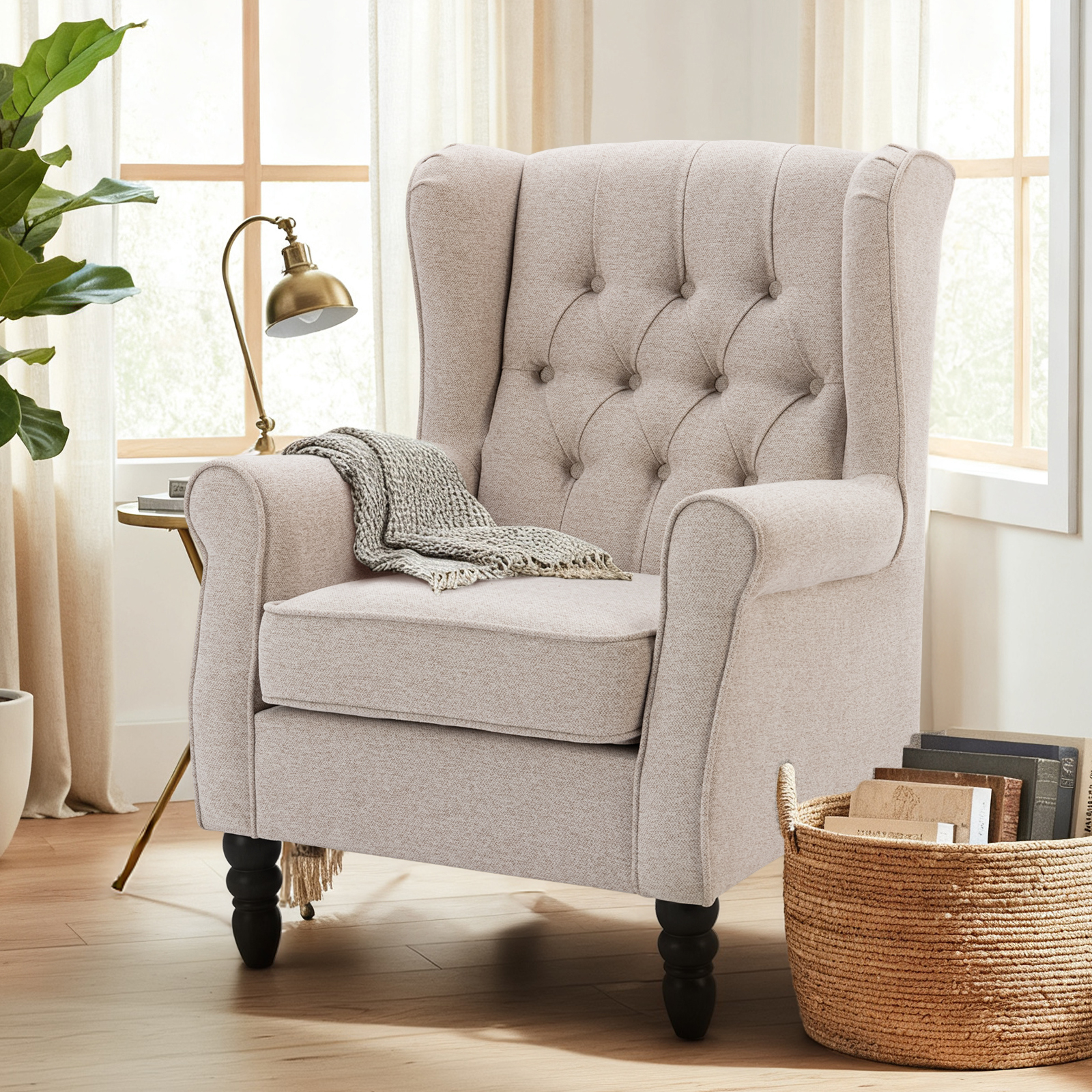 Una poltrona bergère beige con bottoni trapuntati e un plaid, accanto a una finestra.