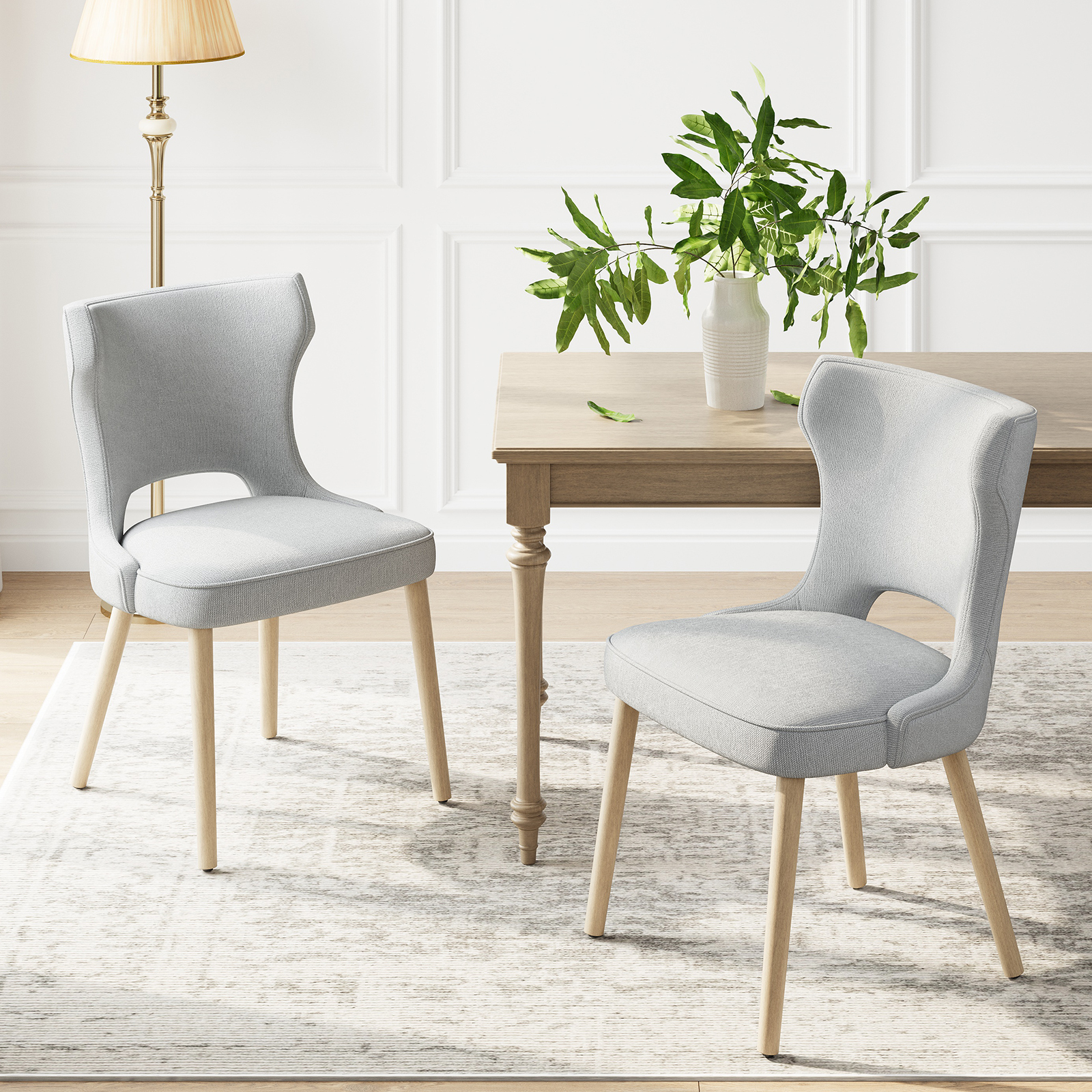 Due sedie grigio chiaro con gambe in legno su un tappeto.