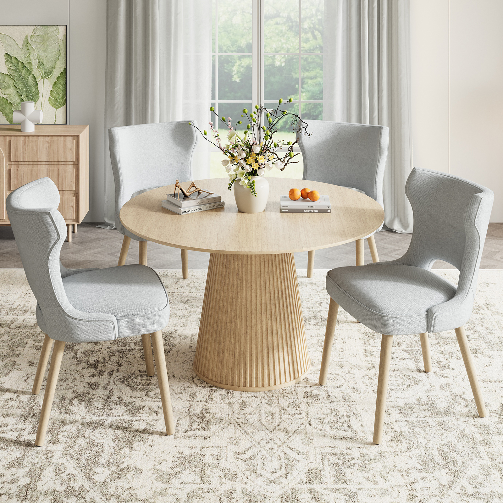 Un tavolo rotondo in legno con quattro sedie grigio chiaro, decorate con fiori e arance.