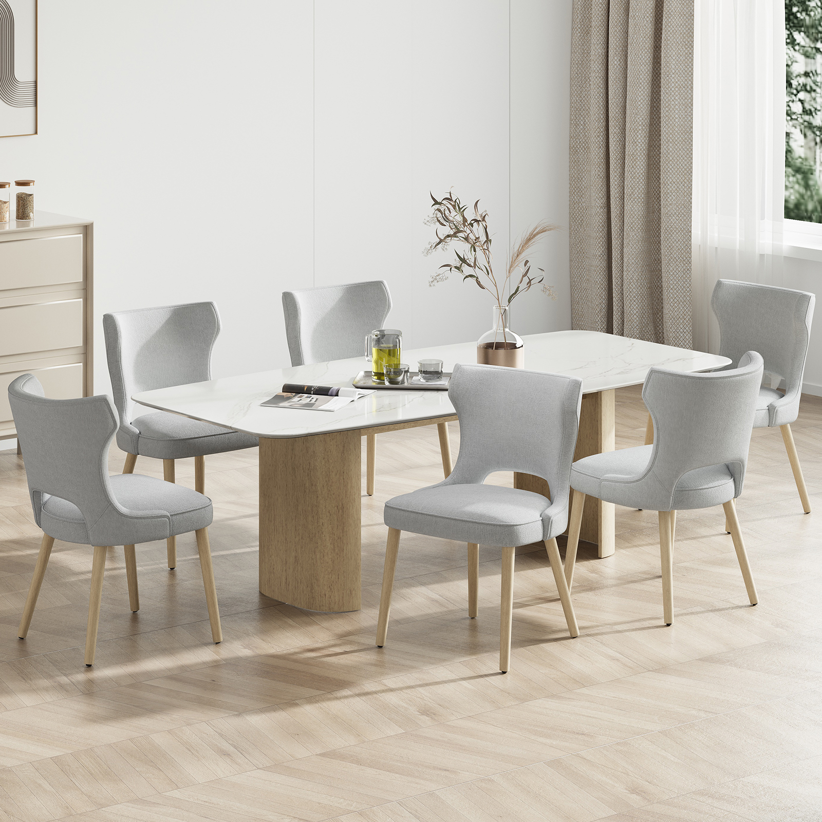 Una luminosa zona pranzo con tavolo bianco, sei sedie grigie e un vaso con rami.