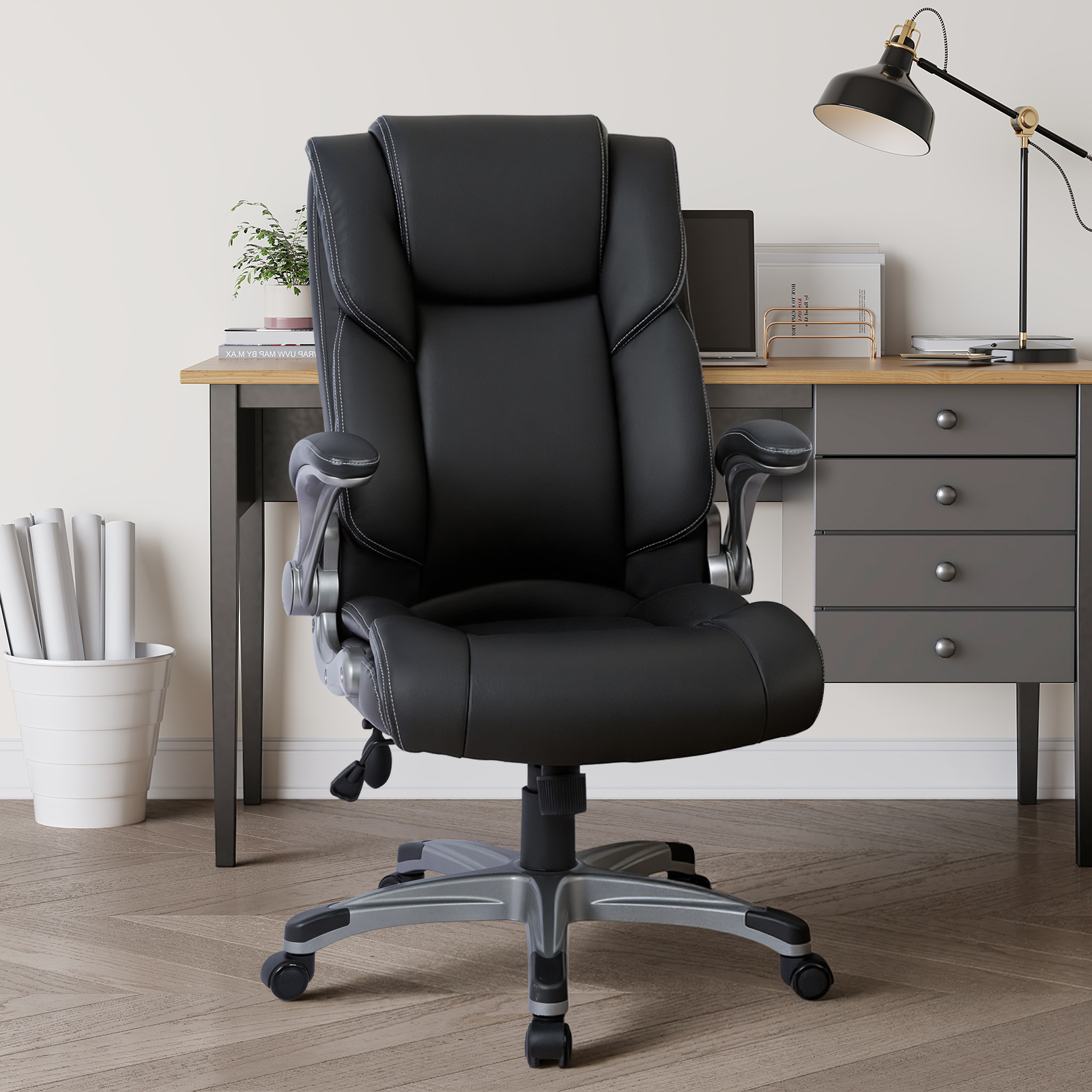 Una silla de oficina negra de respaldo alto está frente a un escritorio con cajones.