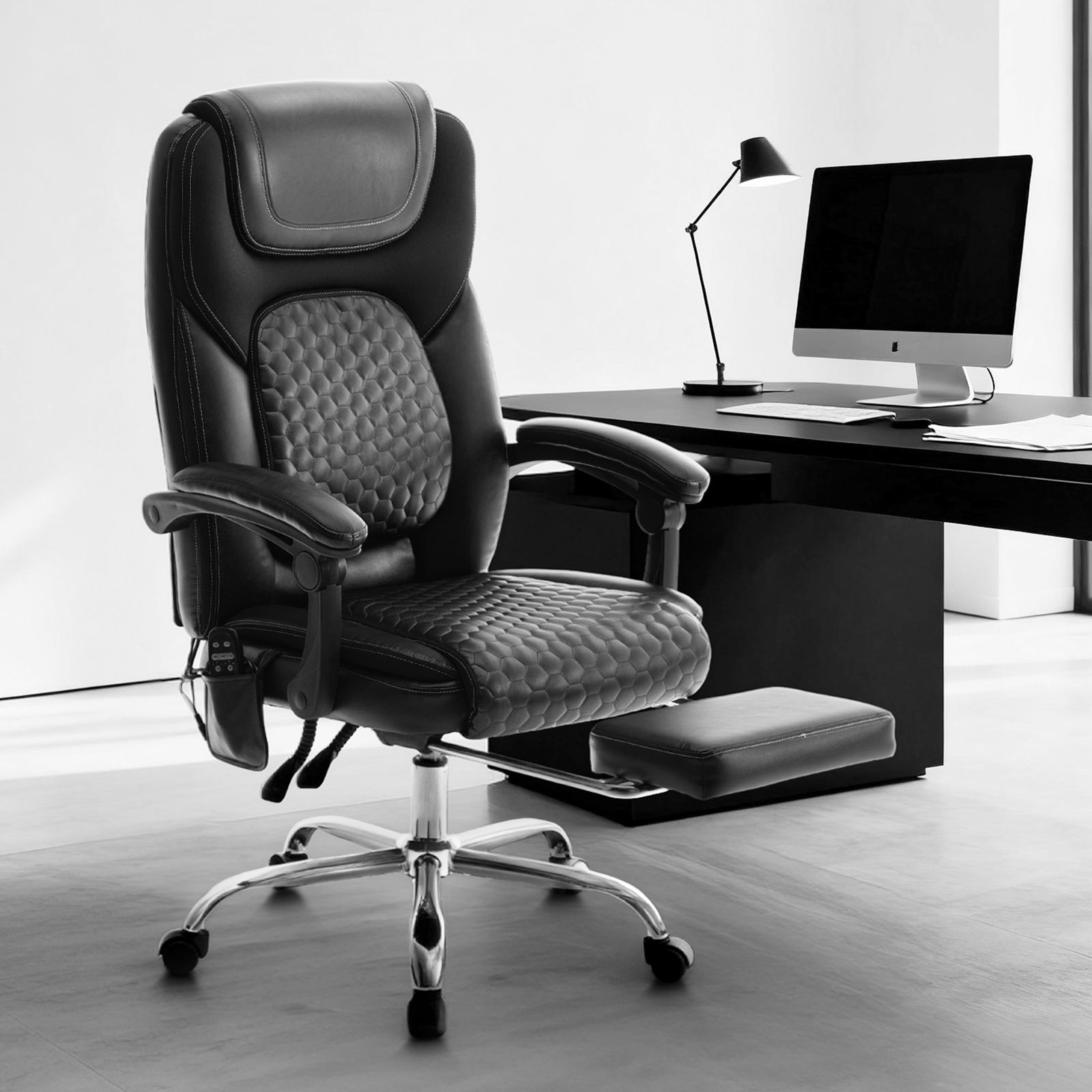 Silla de oficina negra con reposapiés extraíble, escritorio con ordenador y lámpara.