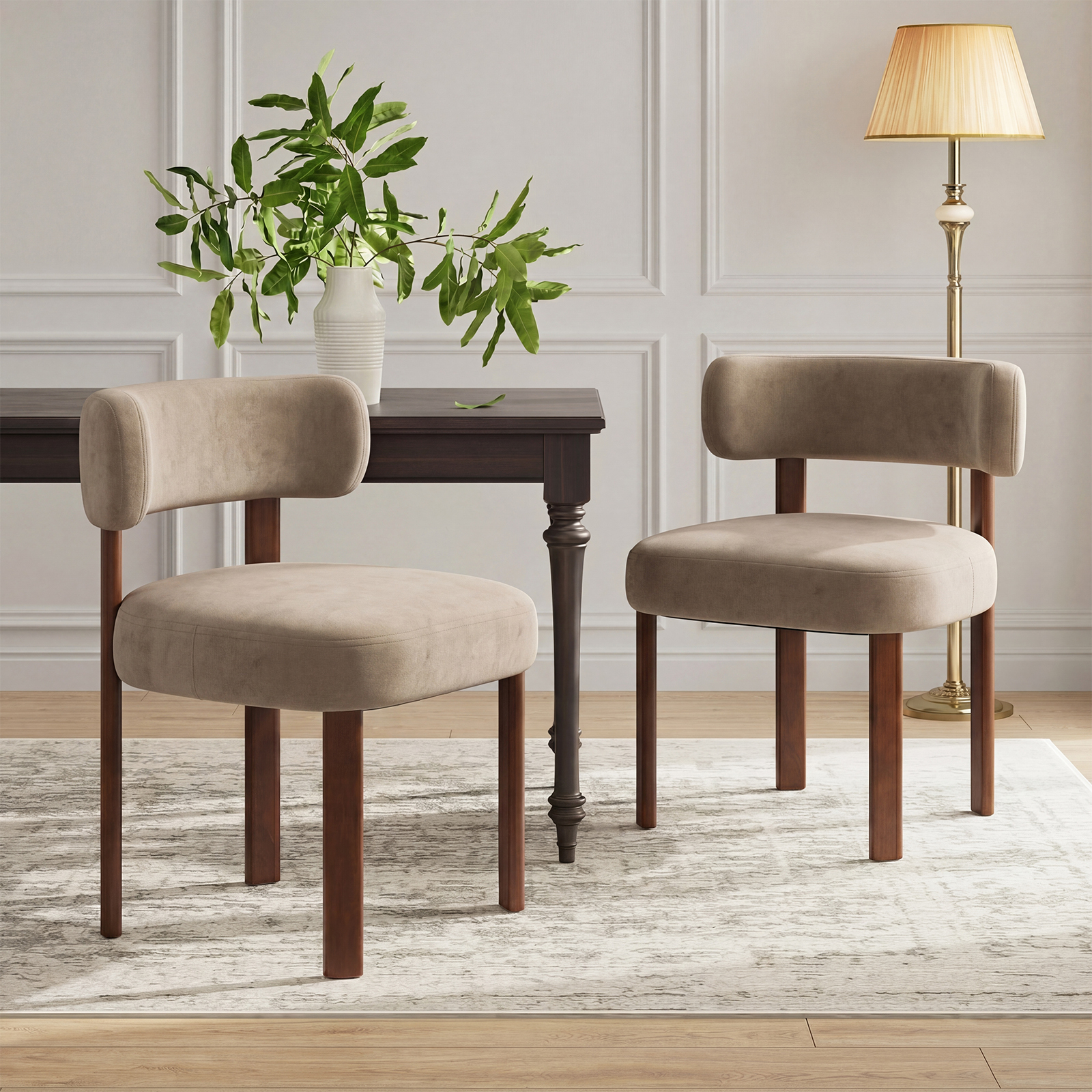 Due sedie beige davanti a un tavolo in legno scuro con vaso e rami.