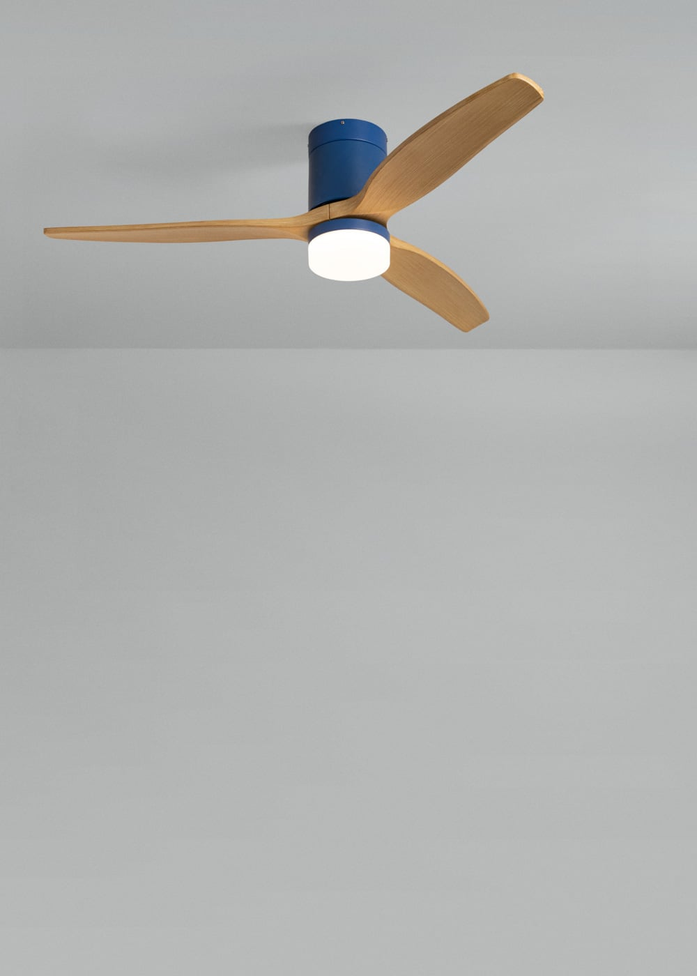 Un ventilador de techo azul con tres aspas de madera y una luz redonda.