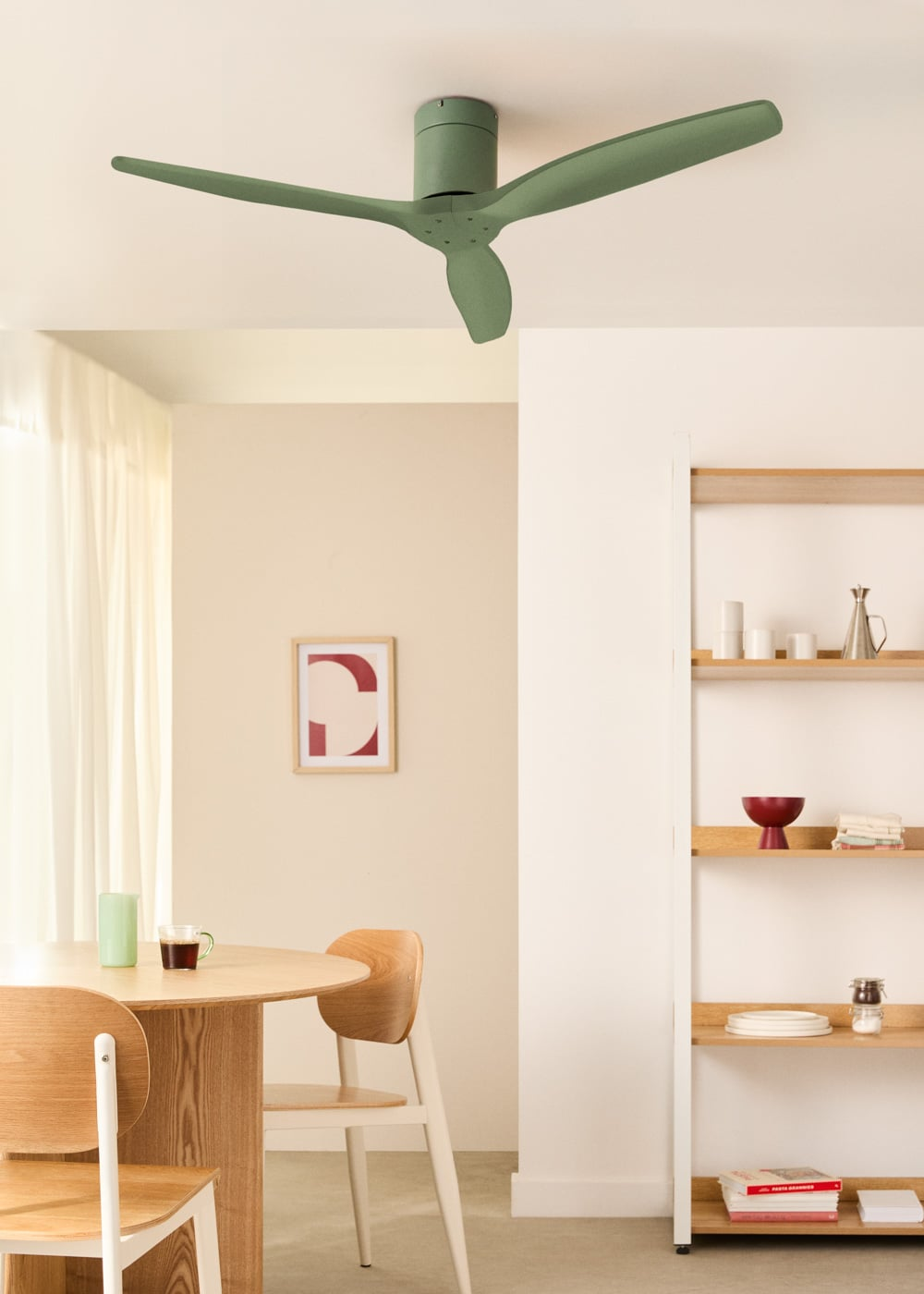 Un ventilador de techo verde sobre una mesa de madera con sillas. Un cuadro abstracto enmarcado cuelga en la pared.