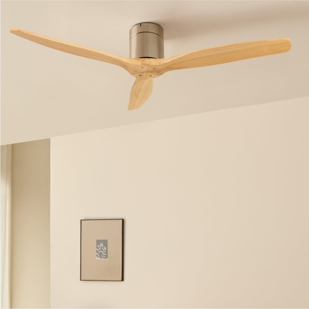 Un ventilador de techo moderno con tres aspas de madera clara y carcasa de motor de metal cepillado.