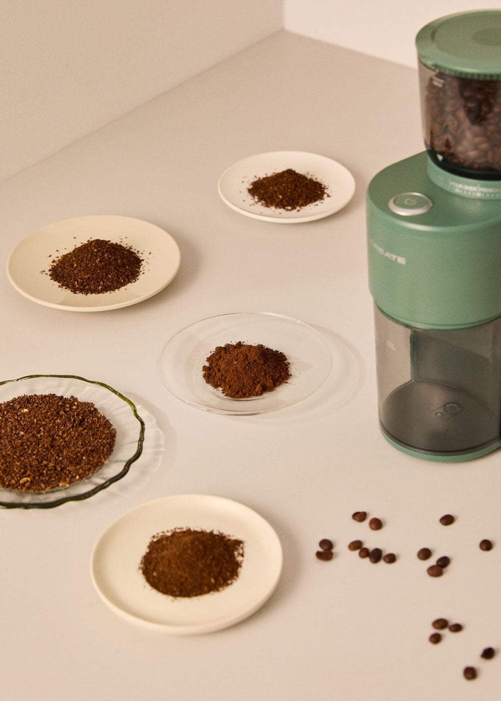 Molinillo de café verde con granos y molido en platos.