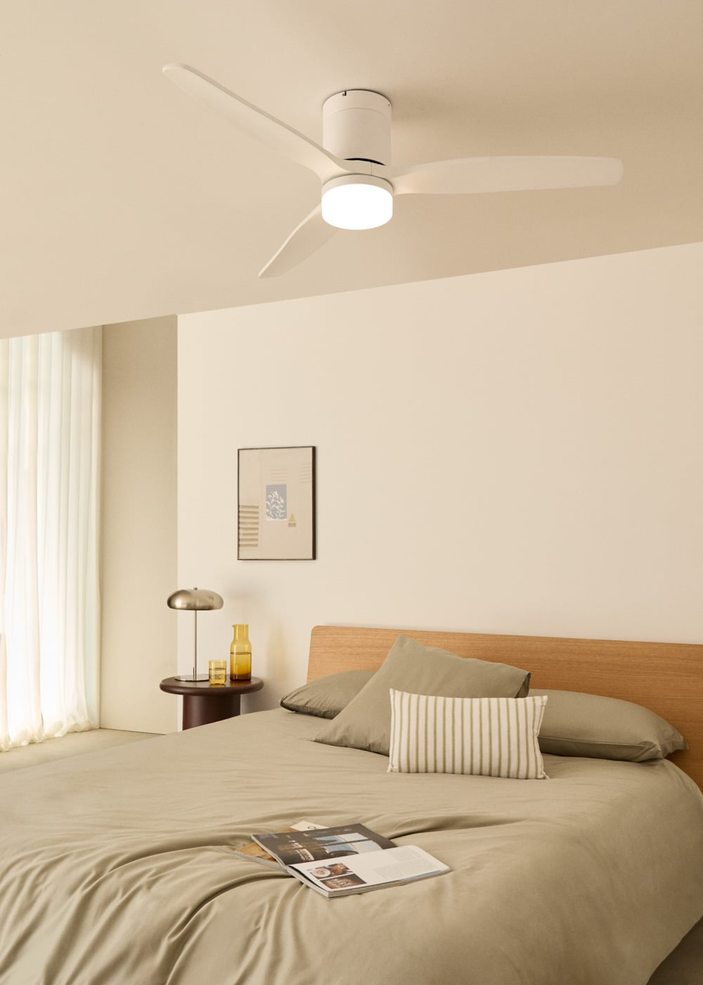 Un ventilador de techo blanco con luz sobre una cama. Una mesita de noche con lámpara.