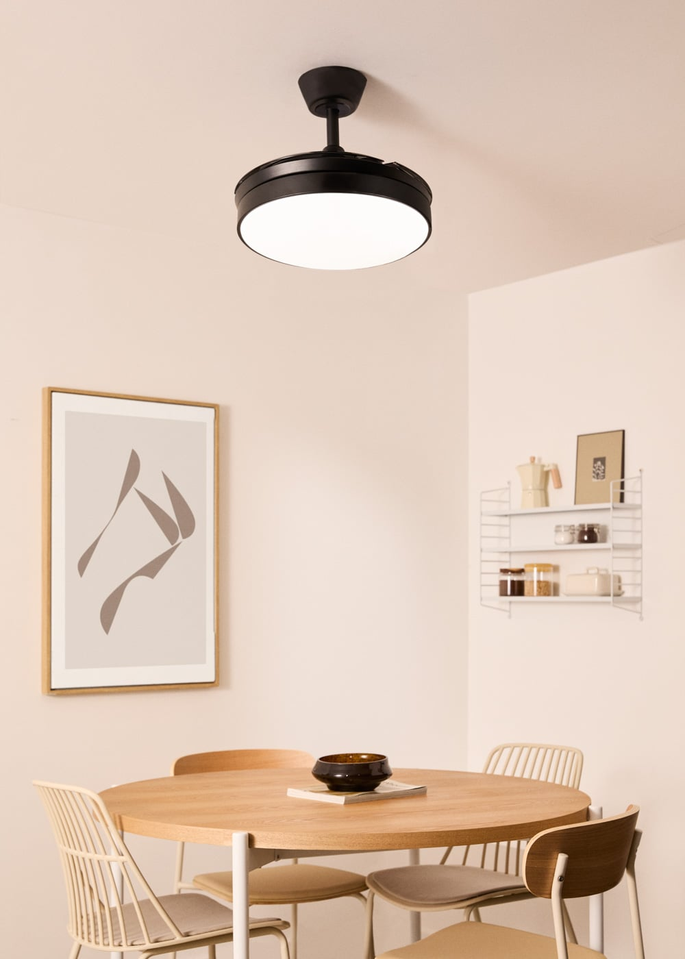 Ventilador de techo negro sobre mesa redonda de madera con sillas.