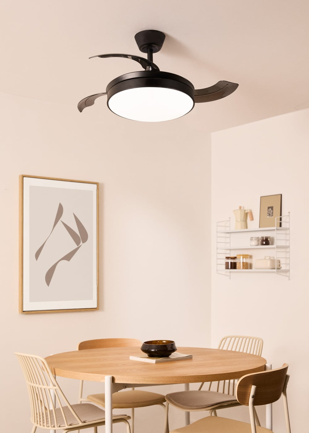 Un comedor moderno con mesa de madera, sillas, arte de pared y ventilador de techo.