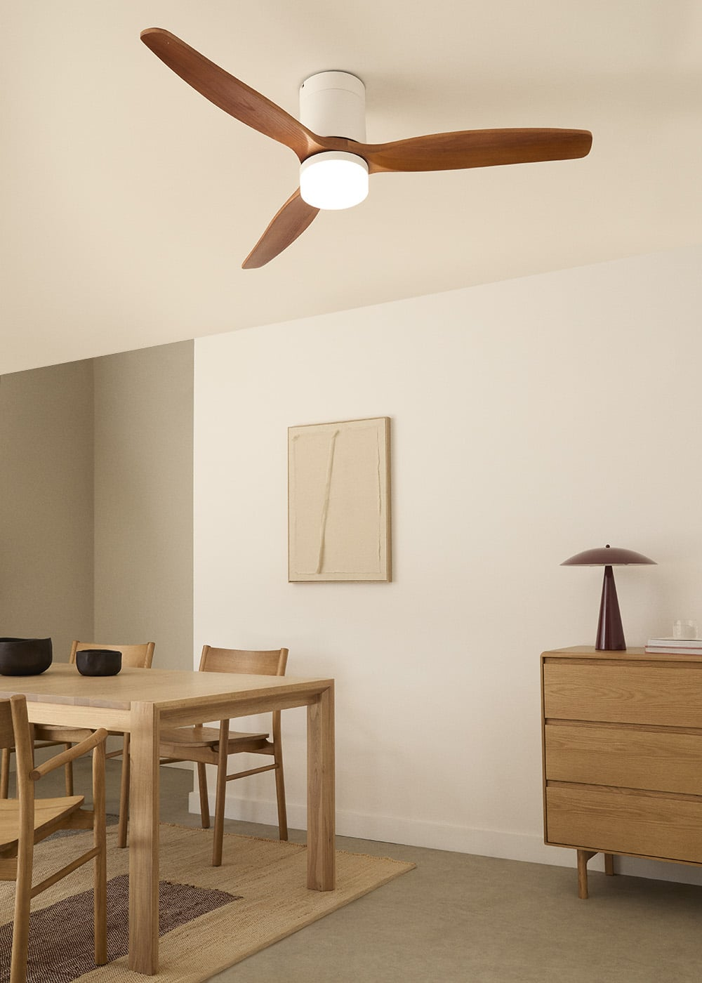 Un comedor con mesa de madera, sillas, ventilador de techo y cómoda.
