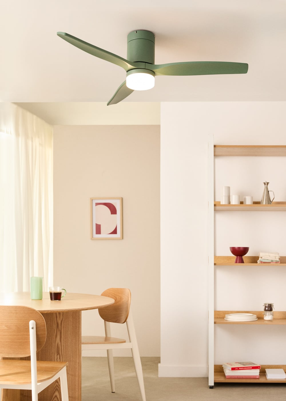 Un ventilador de techo verde con luz sobre una mesa de comedor con sillas.