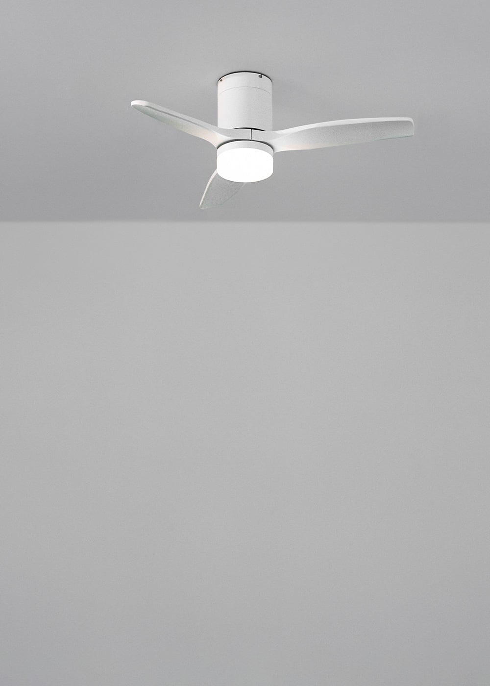 Una luz de ventilador de techo blanca con tres aspas cuelga de un techo gris.