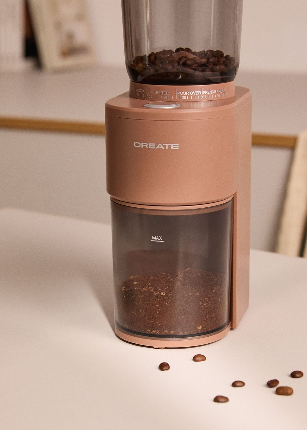 Un molinillo de café rosa con granos arriba y café molido abajo.