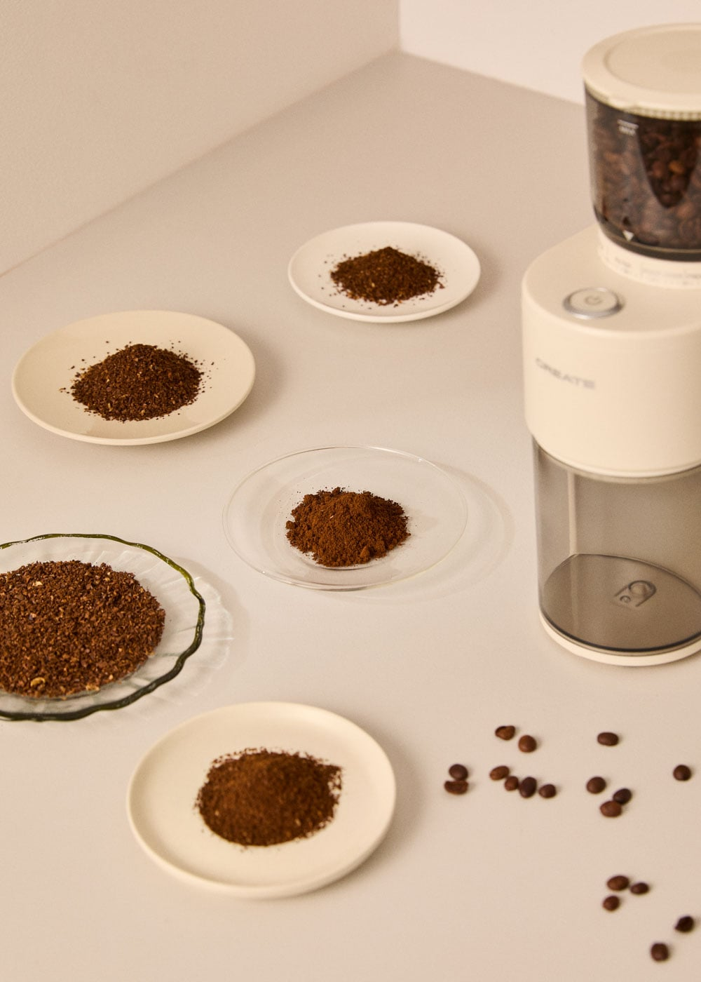 Una cafetera y montones de café molido en platos. Granos de café esparcidos.