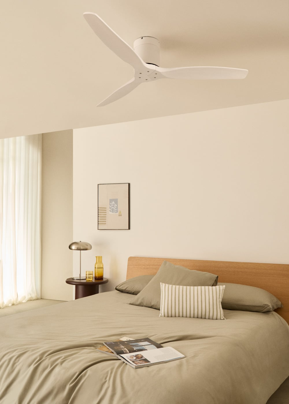 Un ventilador de techo blanco sobre una cama con ropa de cama, almohadas y cabecero de madera.