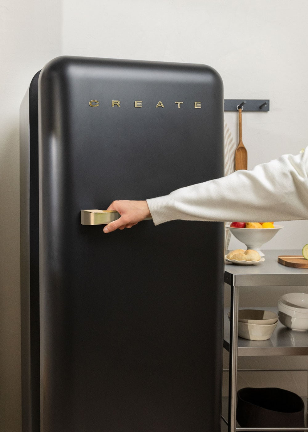 Una mano abre un refrigerador negro con letras doradas.