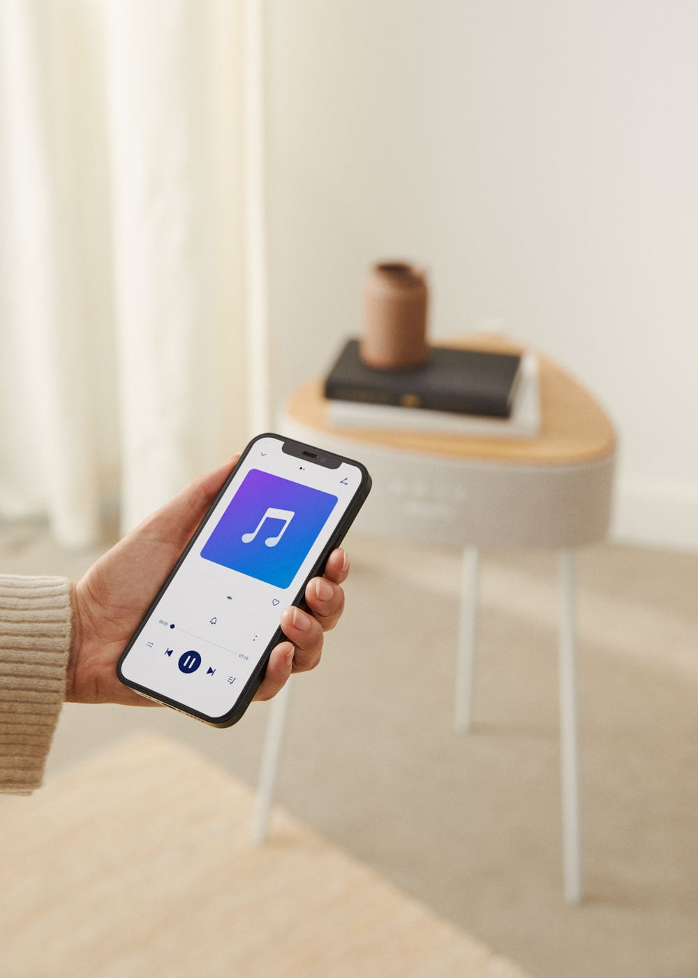 Un teléfono muestra una app de música con un icono de nota musical. Una mesa al fondo.