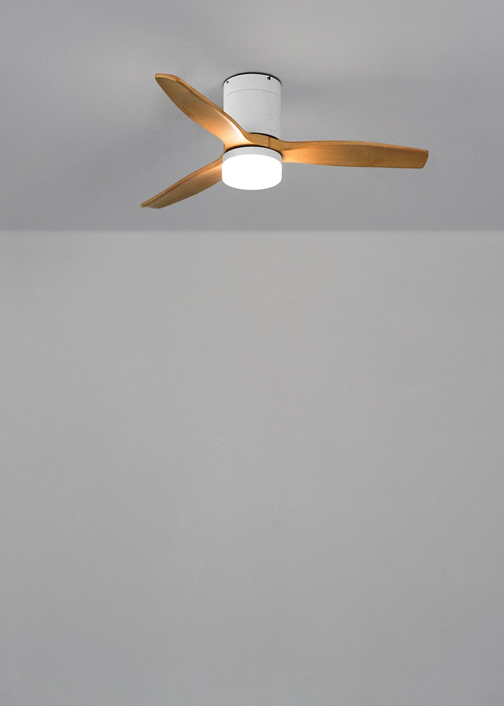 Ventilador de techo con aspas de madera y luz integrada en techo gris.