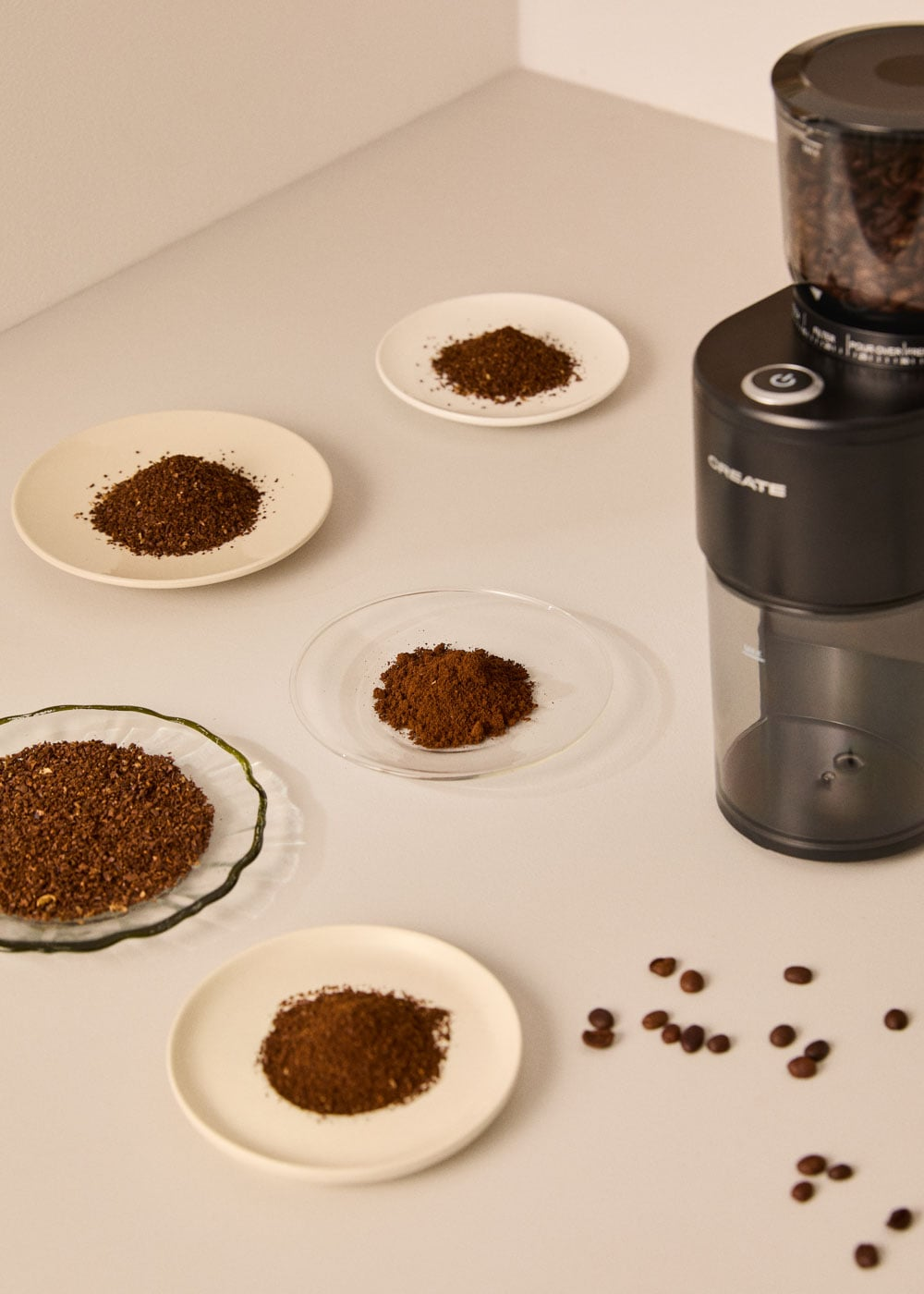 Un molinillo de café con granos de café y café molido en platos.