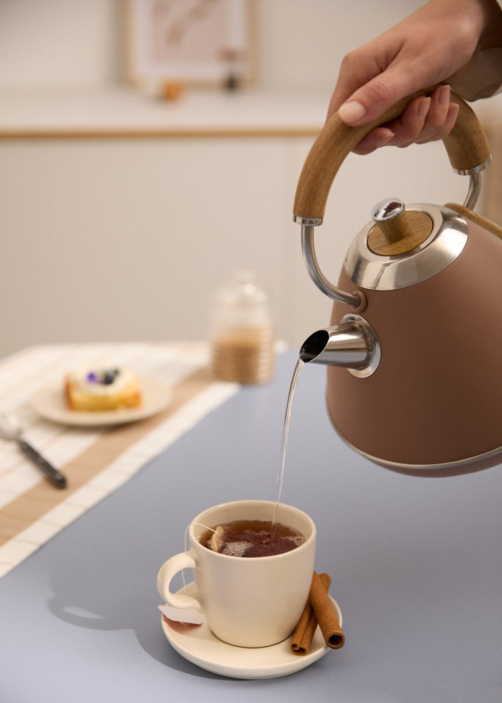 Se vierte líquido caliente de una tetera marrón en una taza blanca.