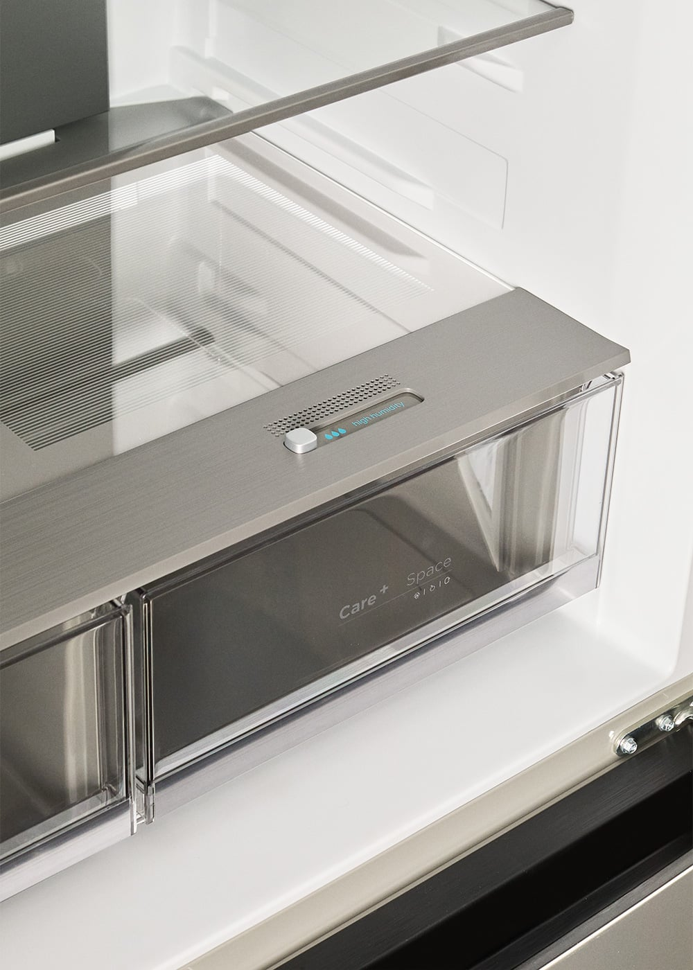 Primer plano de un cajón de refrigerador con control de humedad y etiqueta 'Care+ Space'.