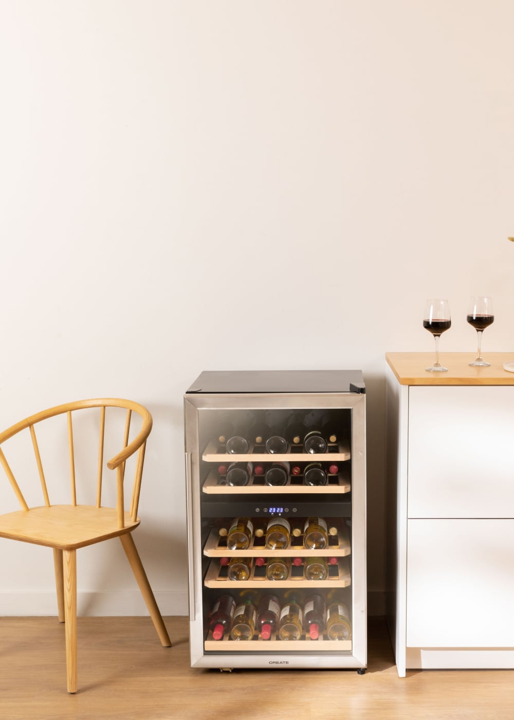 Una vinoteca con botellas, una silla de madera y copas sobre una mesa.