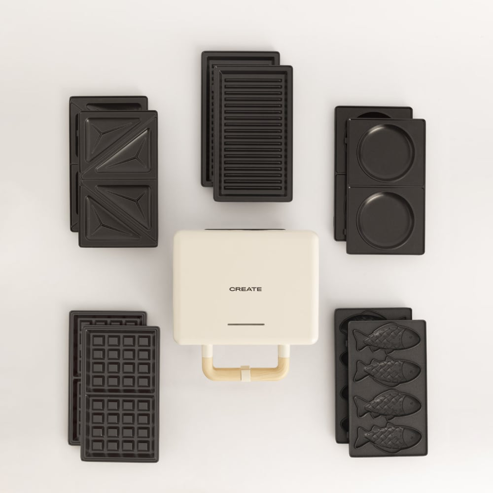 Una sandwichera color crema con varias placas intercambiables.