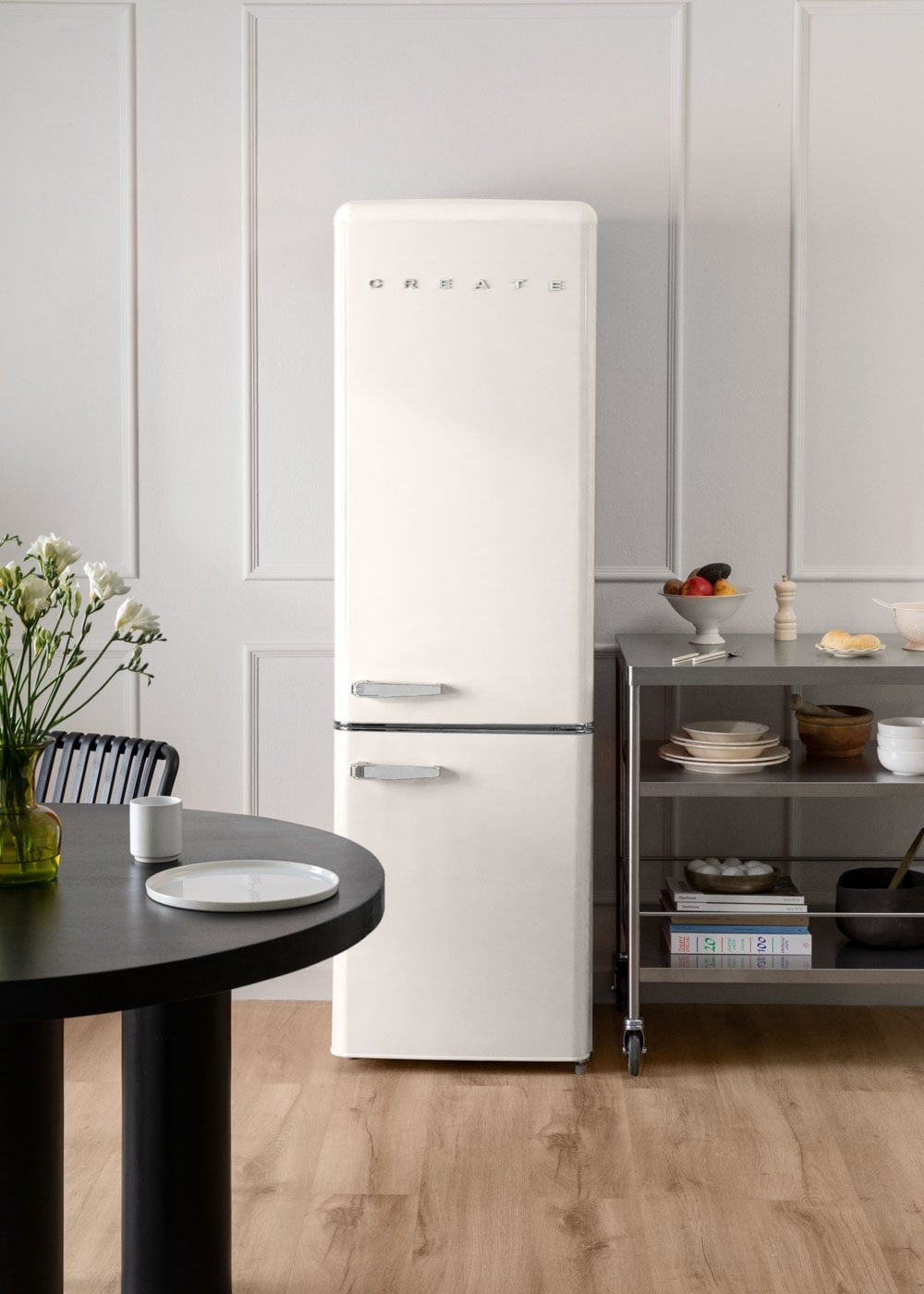 Un refrigerador color crema junto a un estante de metal en una habitación luminosa.