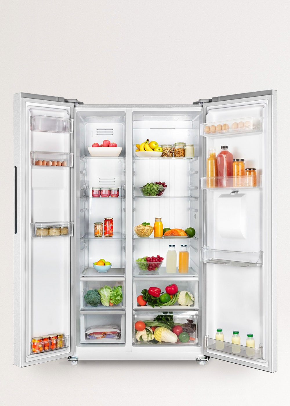 Un refrigerador abierto de dos puertas, lleno de alimentos como frutas, verduras, huevos y bebidas.
