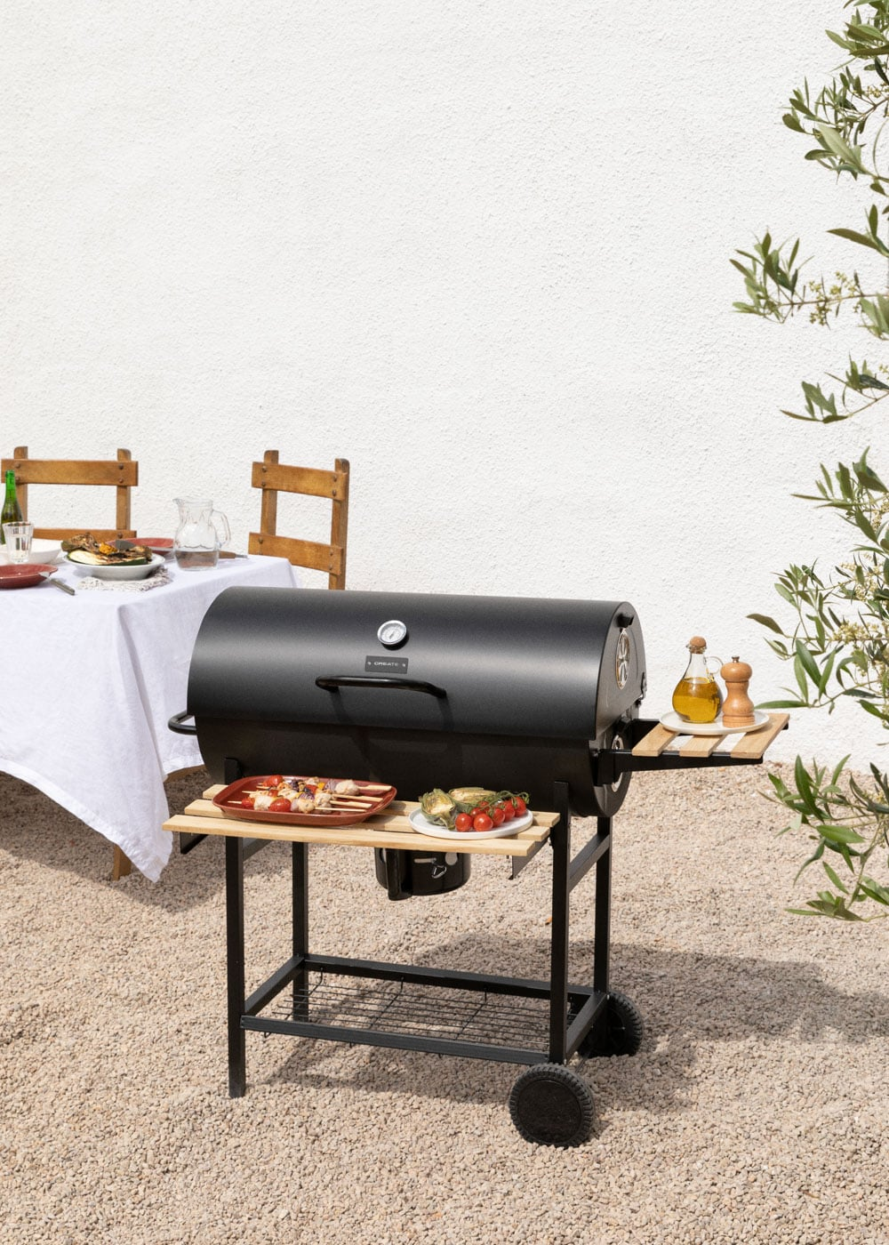 Una parrilla negra al aire libre junto a una mesa puesta con comida.
