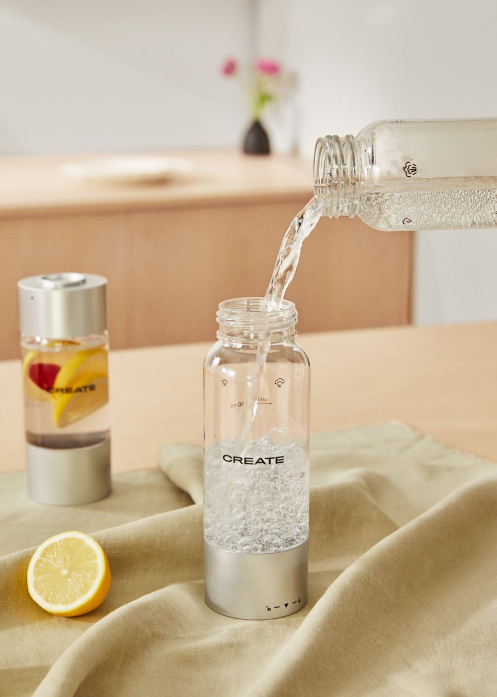 El agua se vierte en una botella de vidrio con base plateada. Otra botella con limón está al lado.