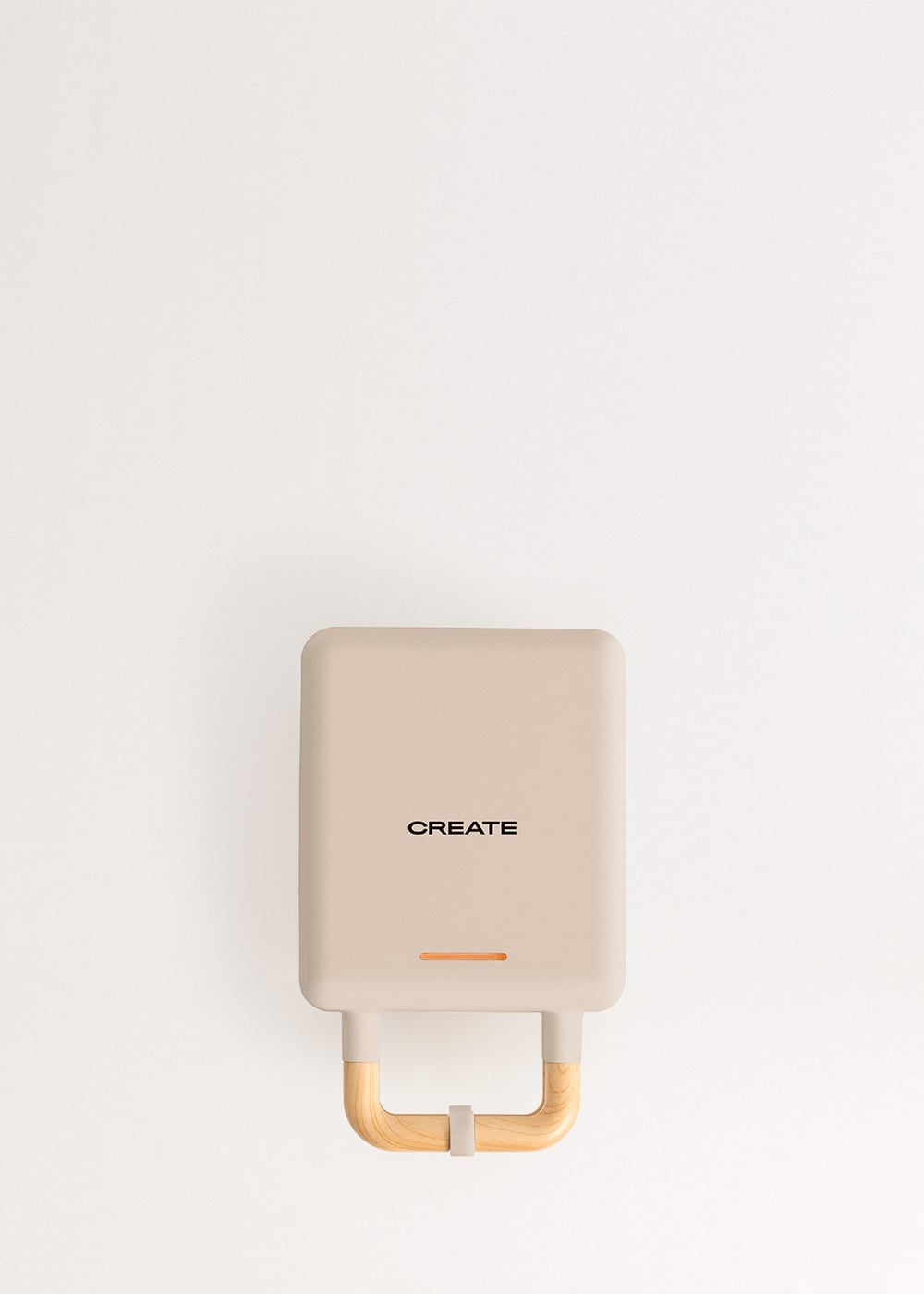 Una gofrera beige con mango de madera y la palabra CREATE.