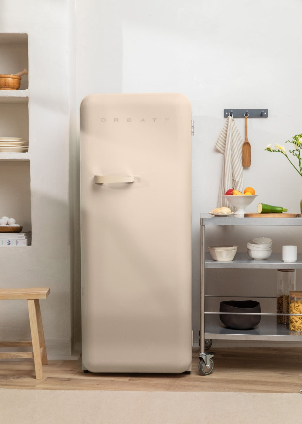 Una nevera beige junto a una estantería con fruta y cuencos.
