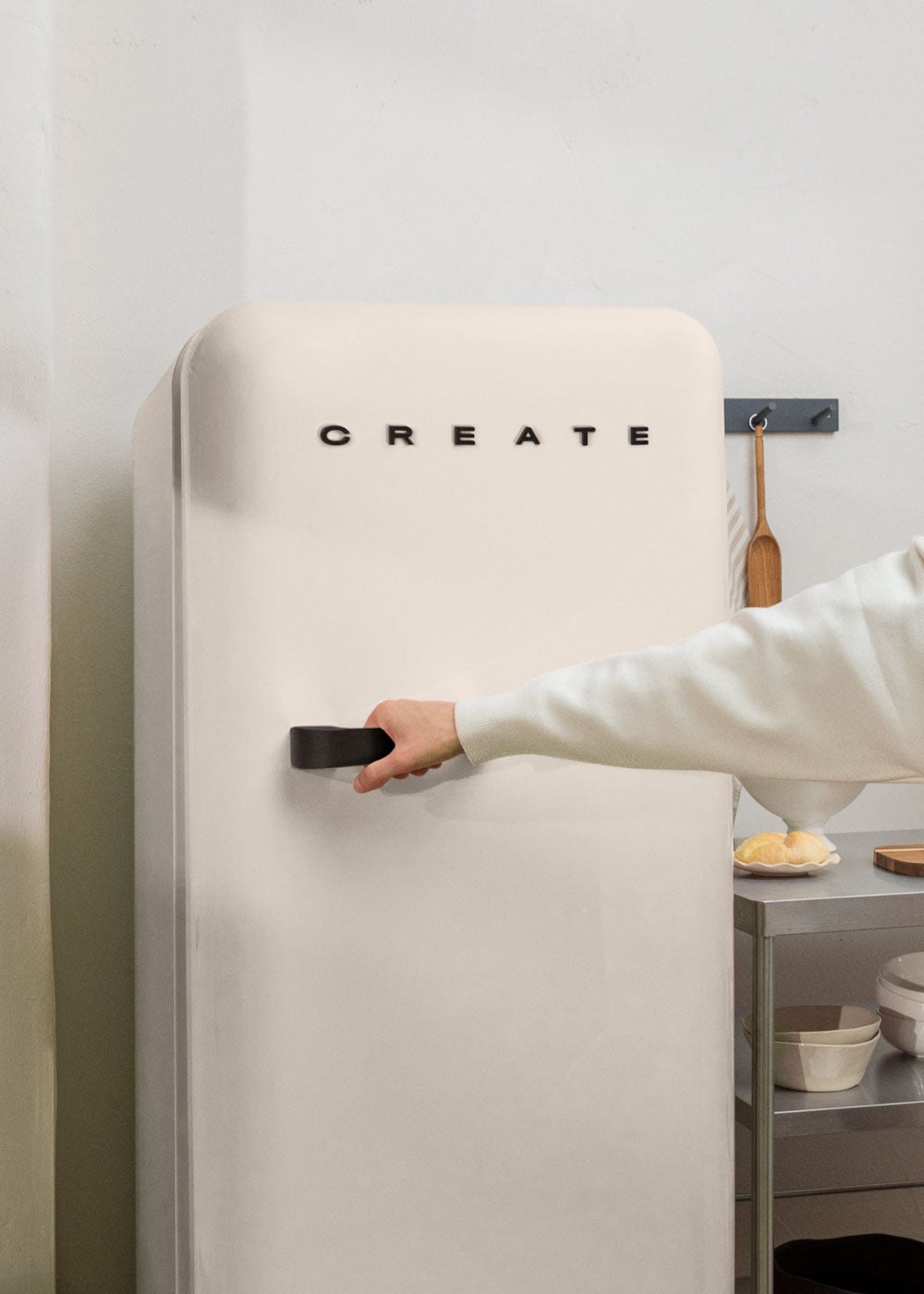 Una mano abre un refrigerador color crema con la palabra CREATE.