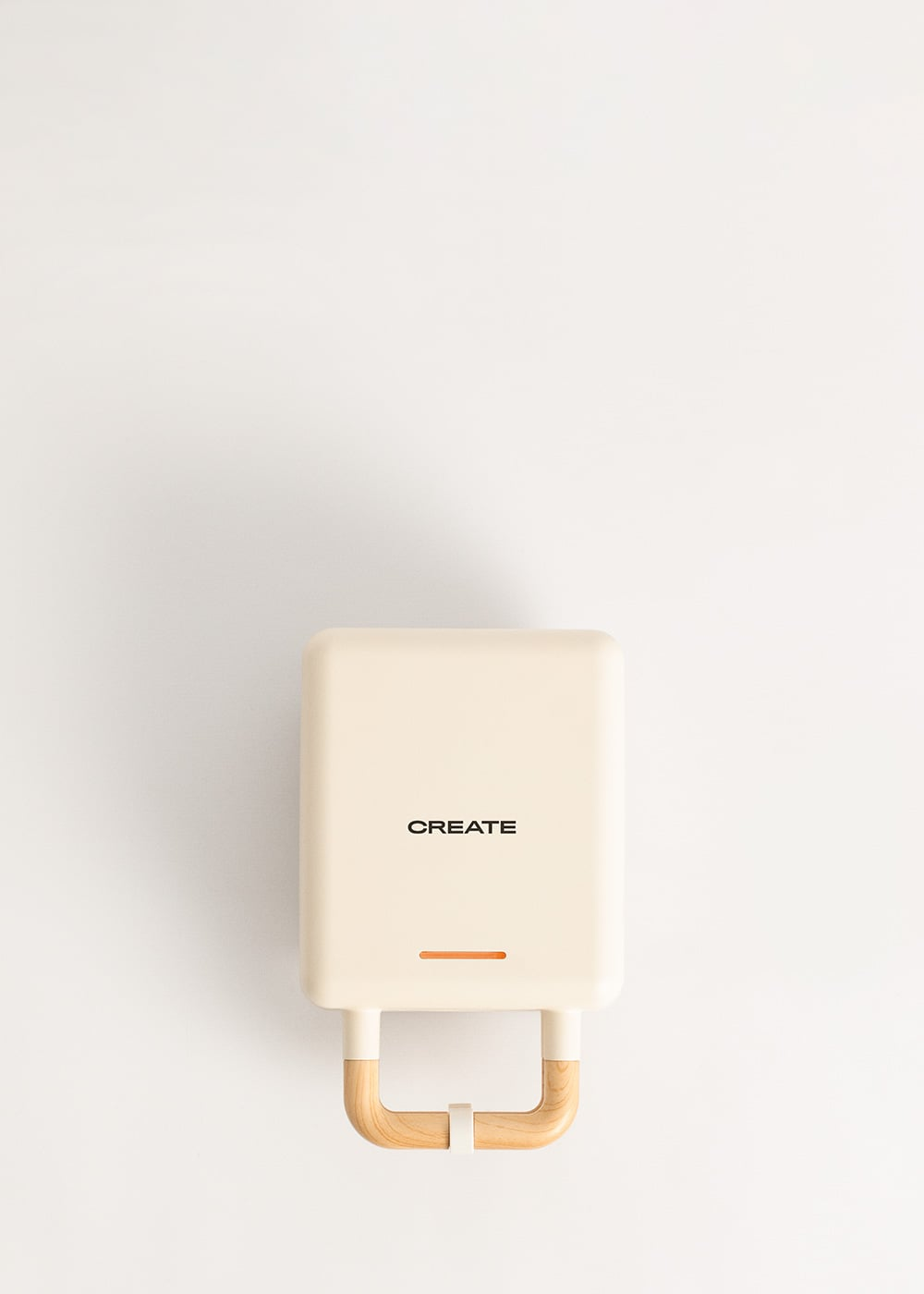 Una gofrera color crema con la palabra CREATE y asas de madera.